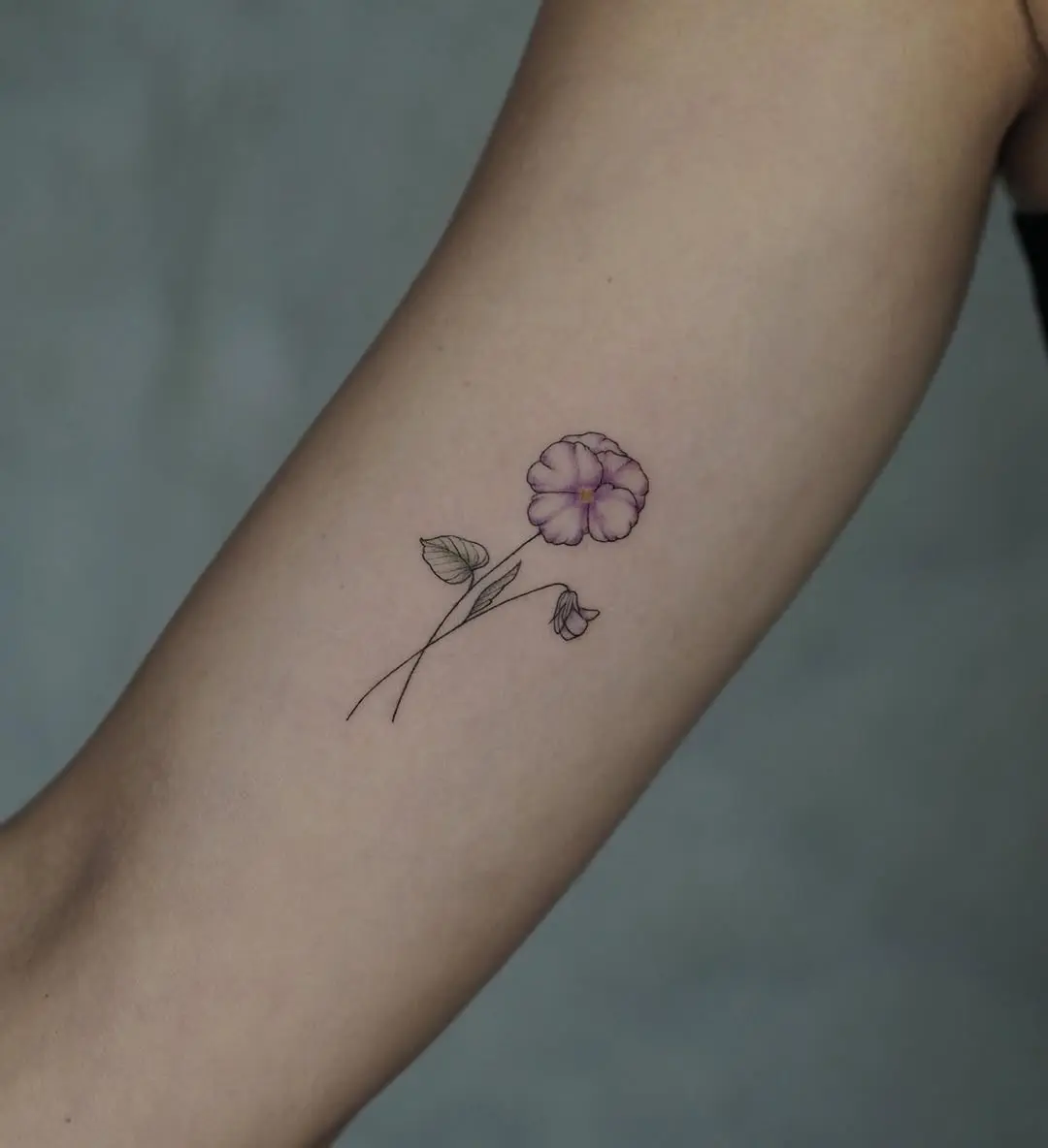 Delicate violet flower tattoo on inner arm