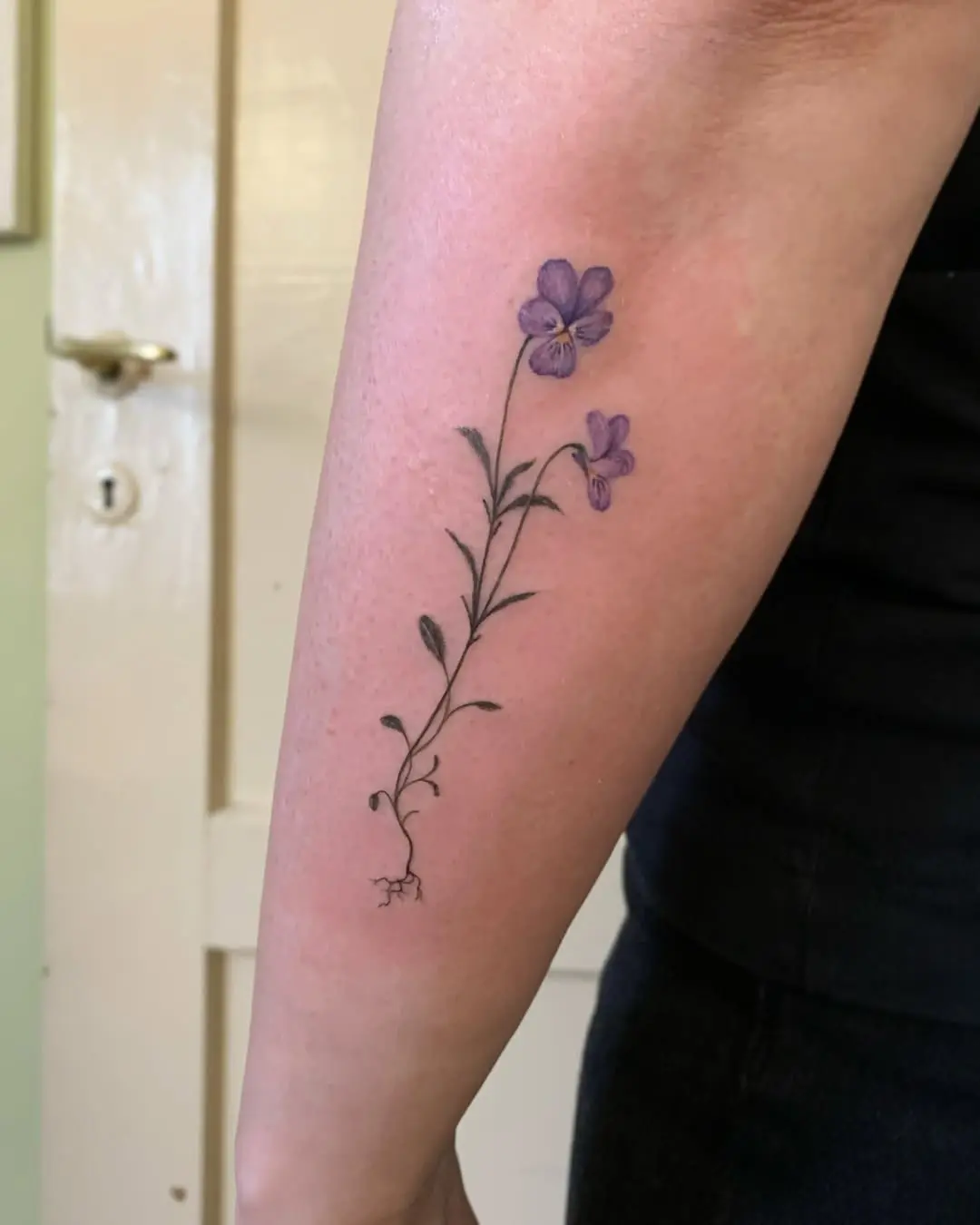 Elegant violet floral tattoo on the forearm