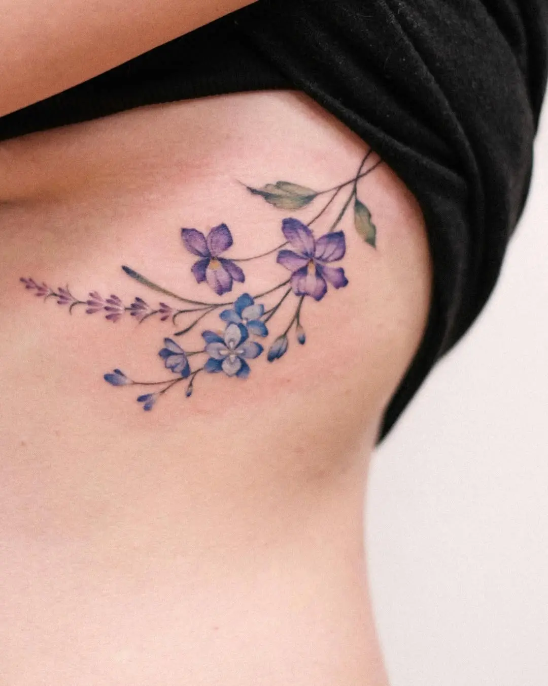Elegant violet floral tattoo on the ribs