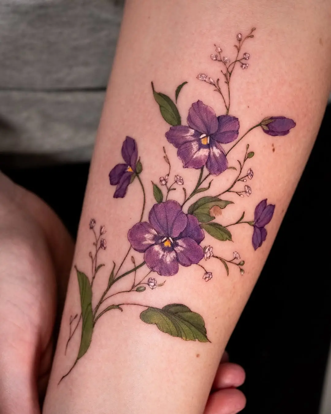 Elegant violet floral tattoo on the forearm