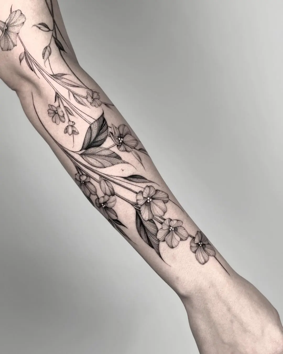 Elegant violet floral tattoo design on forearm