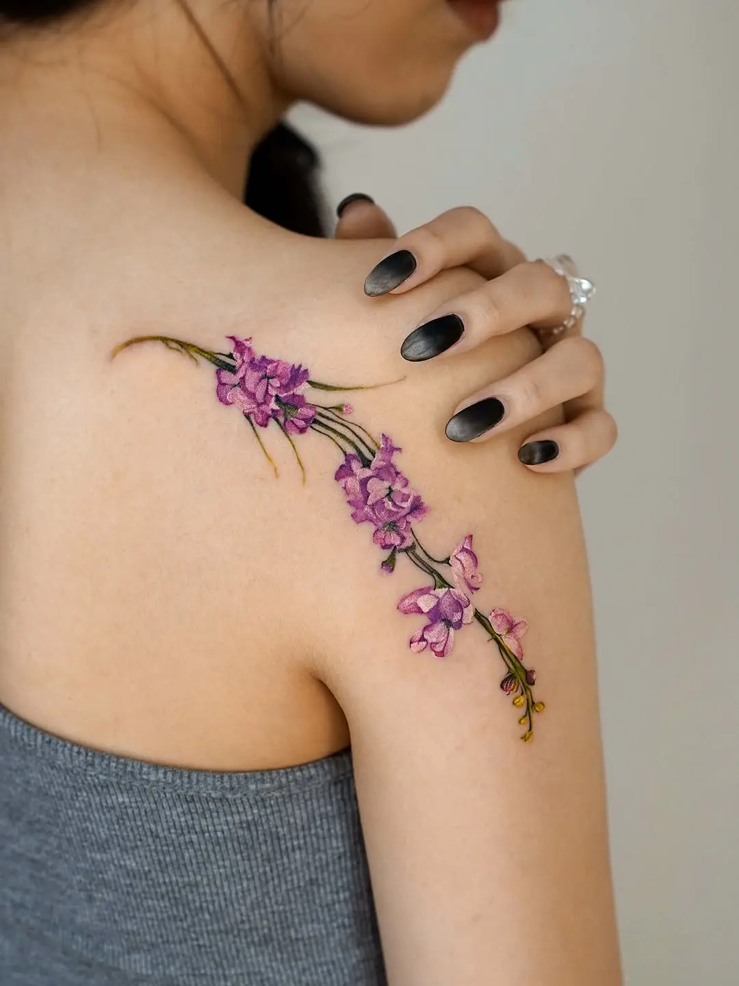 Delicate violet flower tattoo on shoulder.