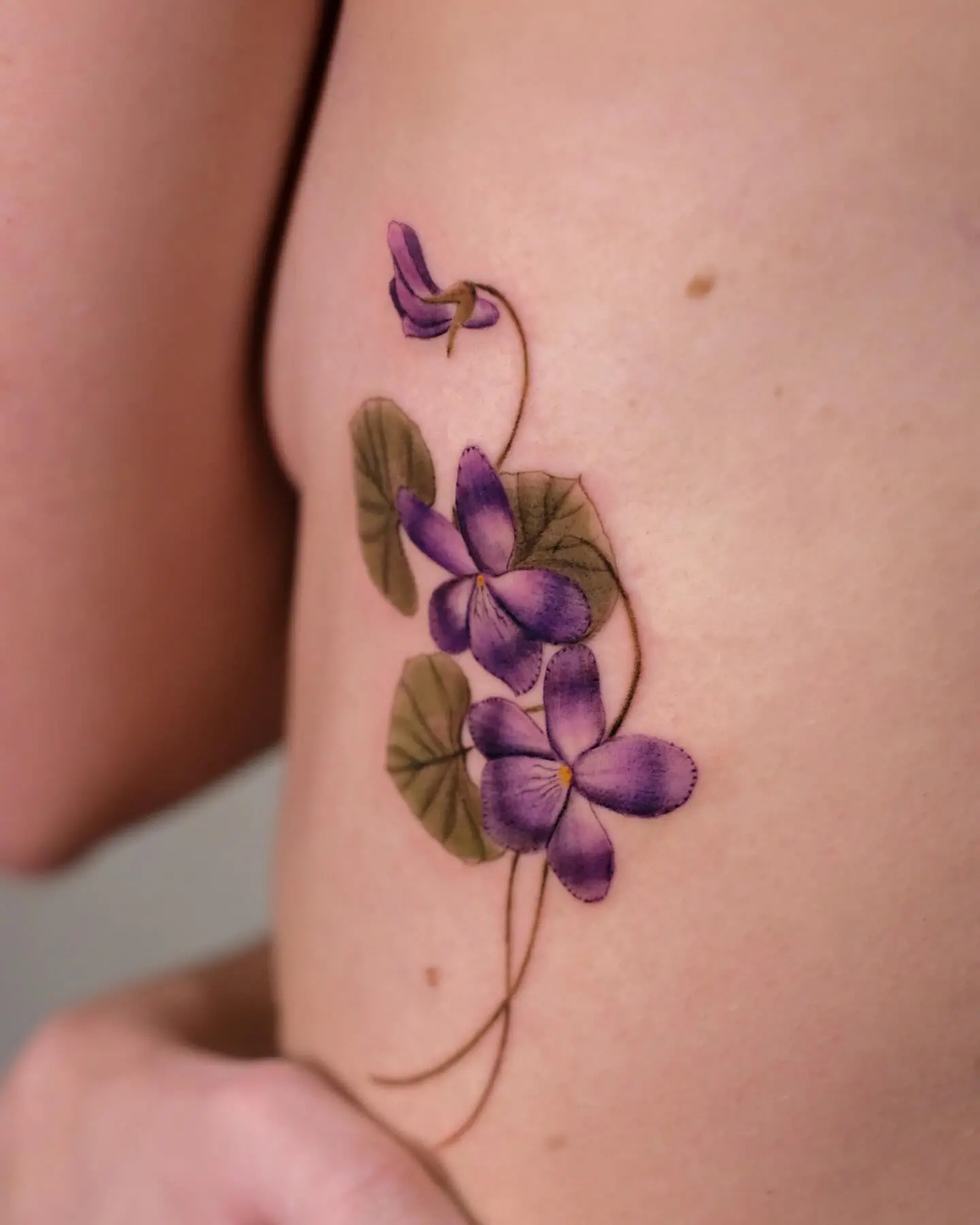 Elegant violet floral tattoo on the skin
