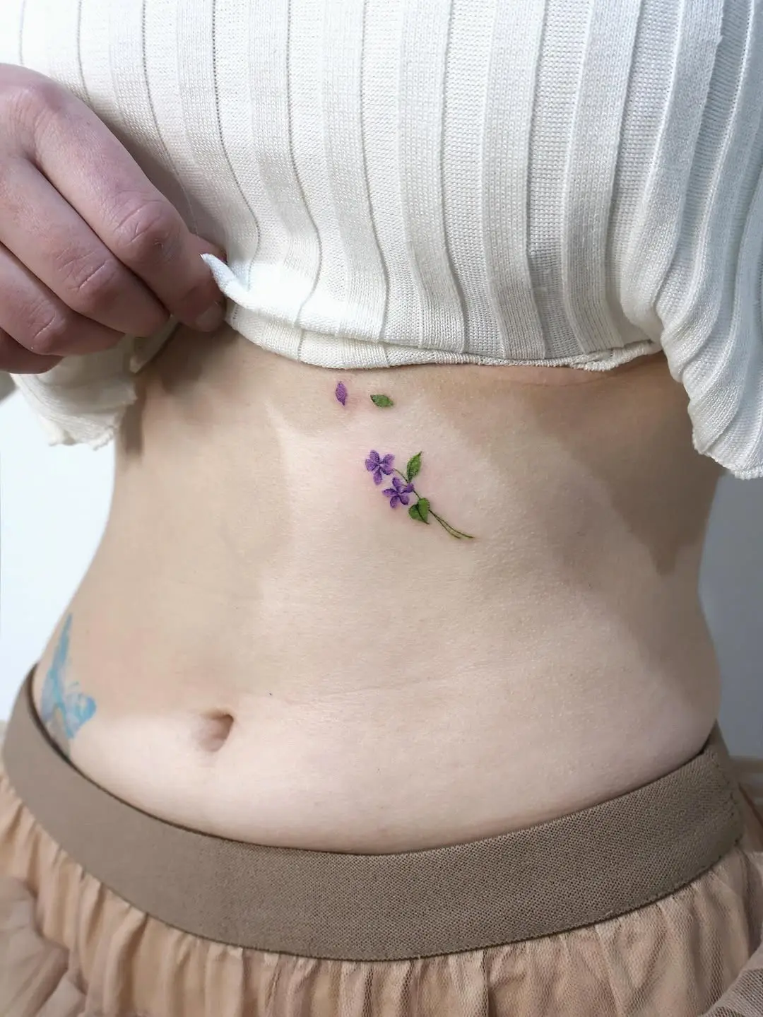 Delicate violet tattoo on the lower abdomen