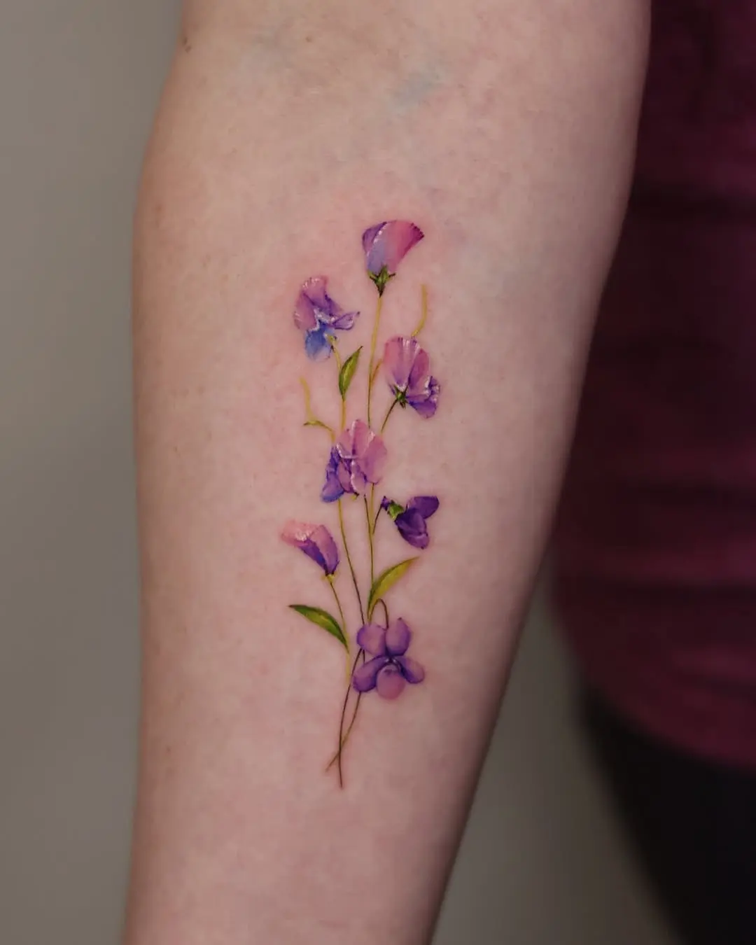 Delicate violet flower tattoo on the arm