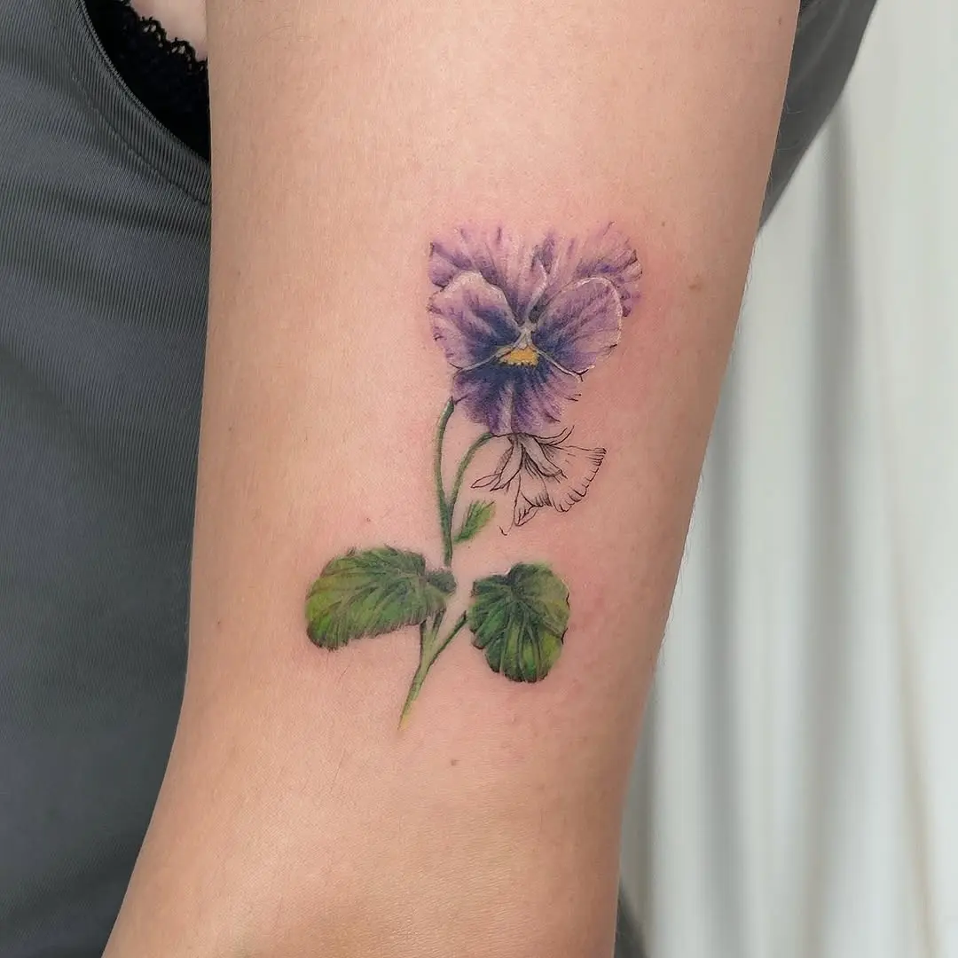 Delicate pansy tattoo showcasing vibrant violet hues