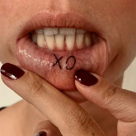 Inner lip tattoo with bold XO lettering