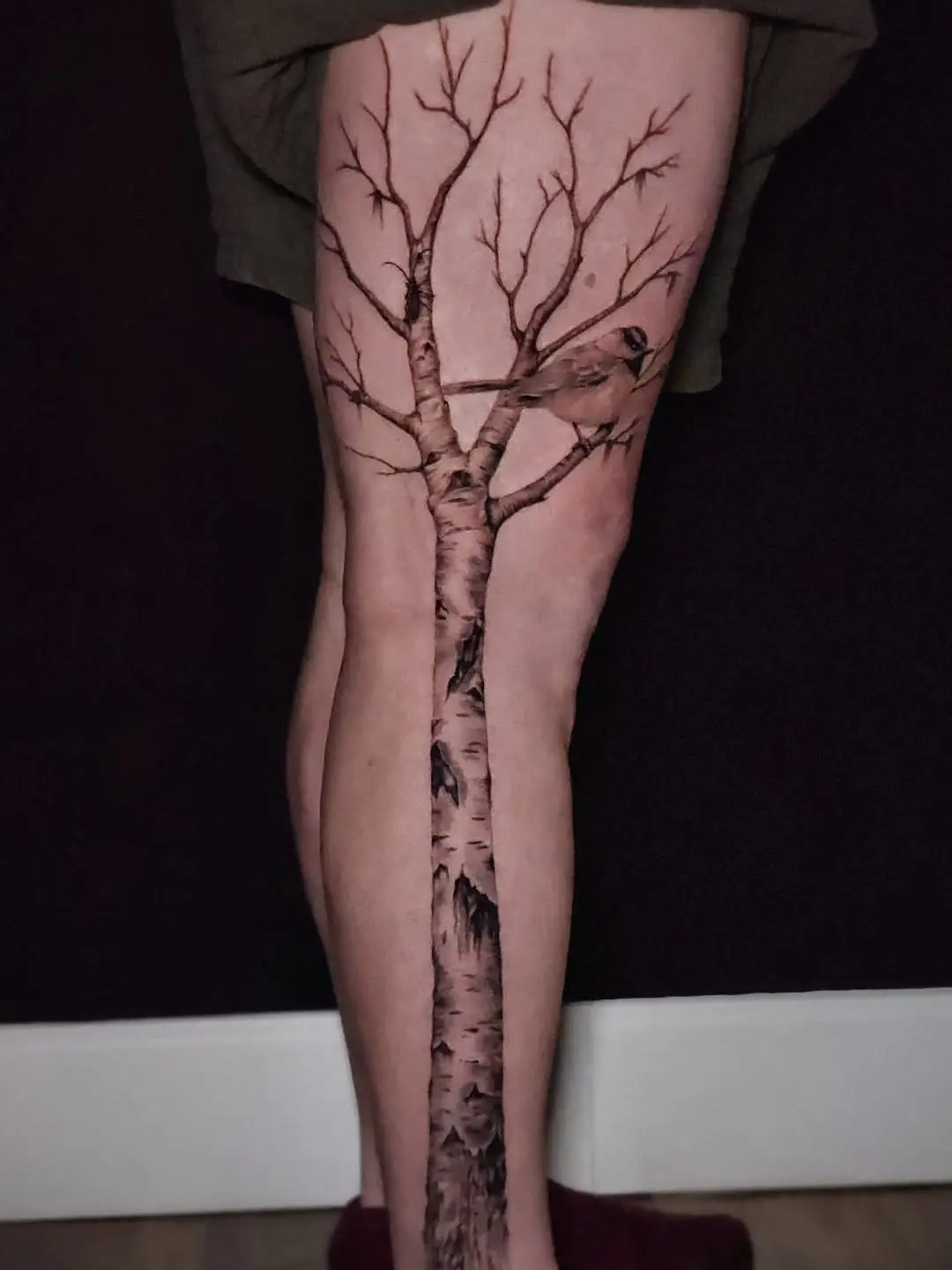 Elegant birch tree and bird leg tattoo design