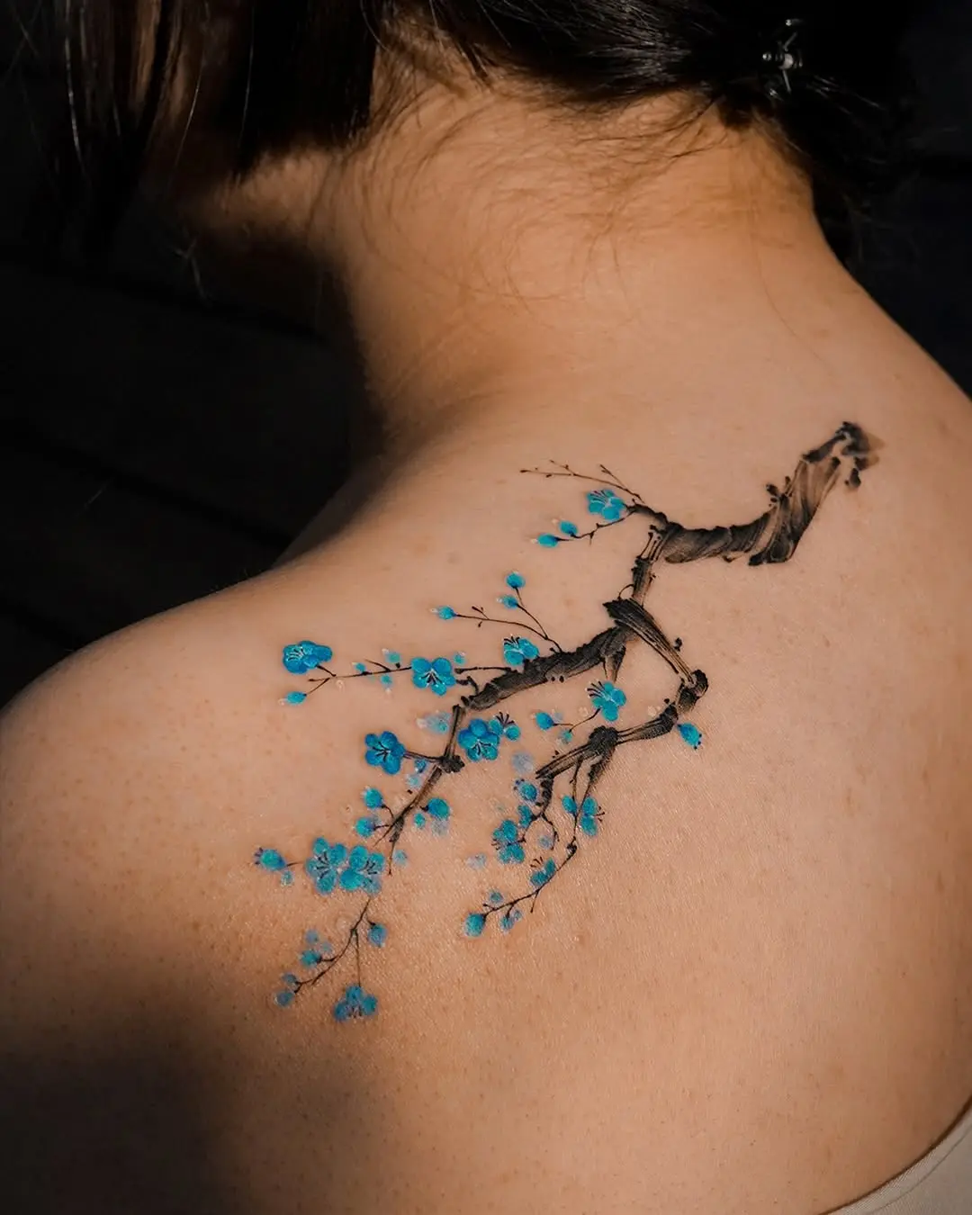 Elegant branch tattoo with blue blossoms