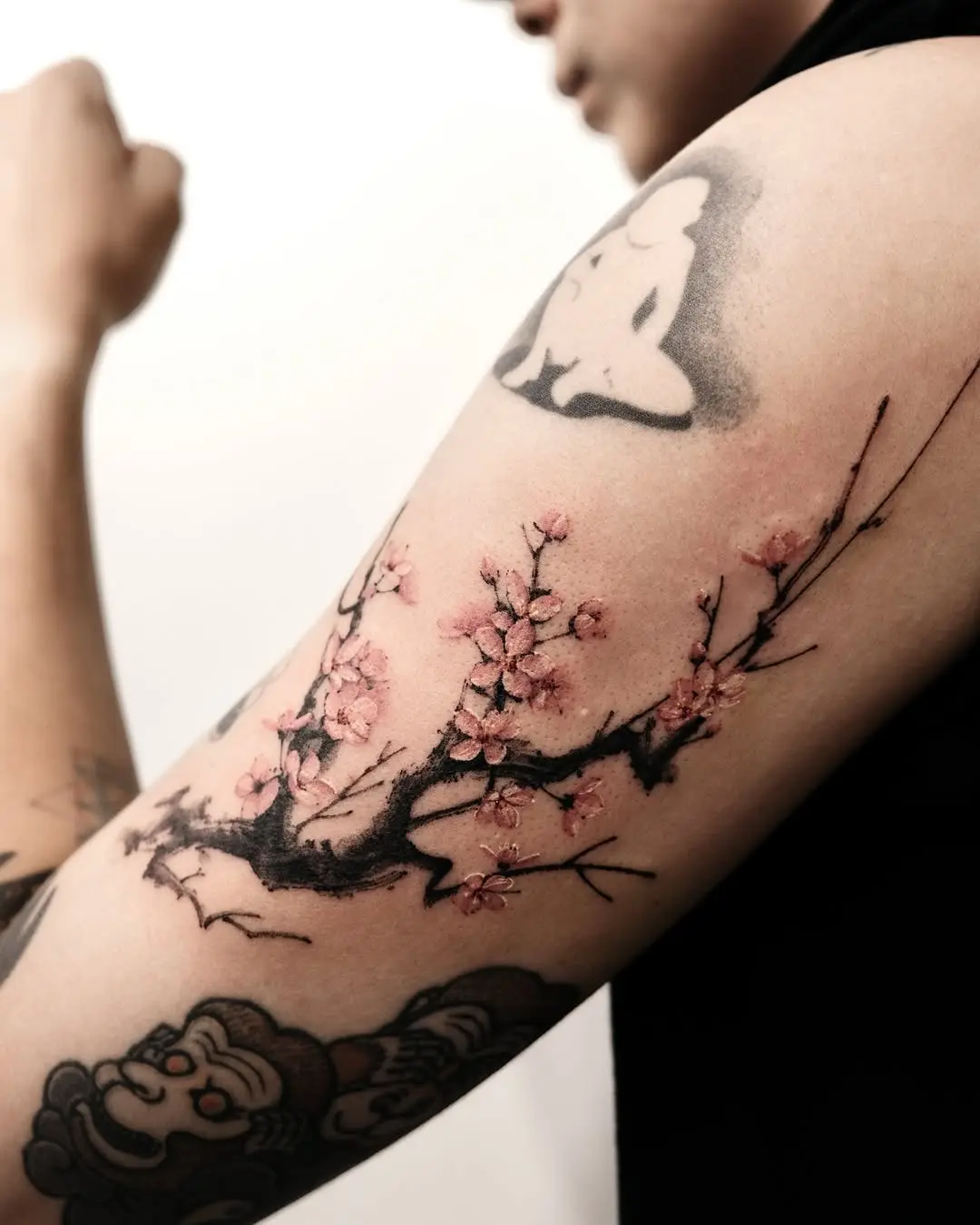 Delicate cherry blossom branch tattoo on arm