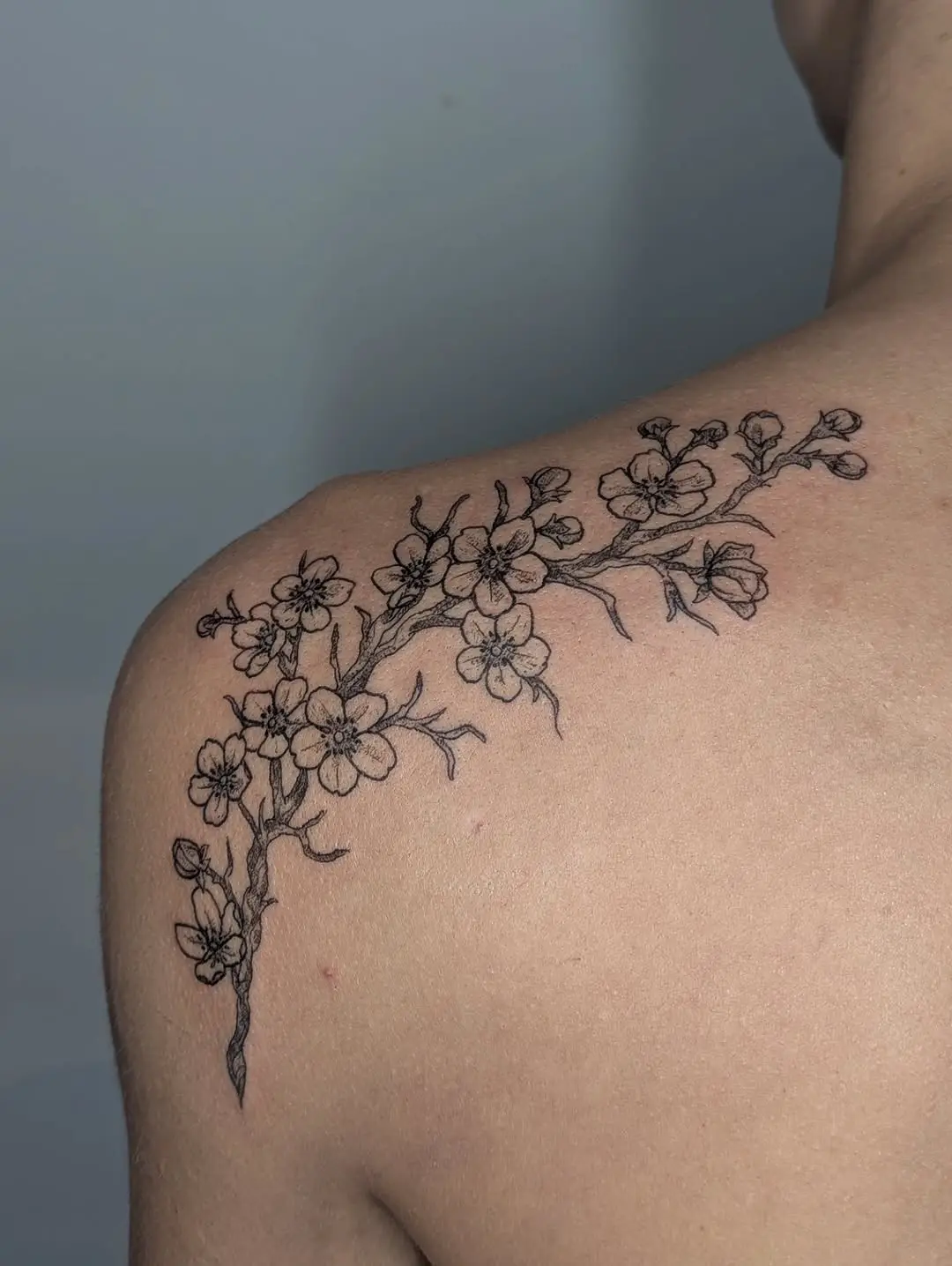 Elegant floral branch tattoo on the shoulder