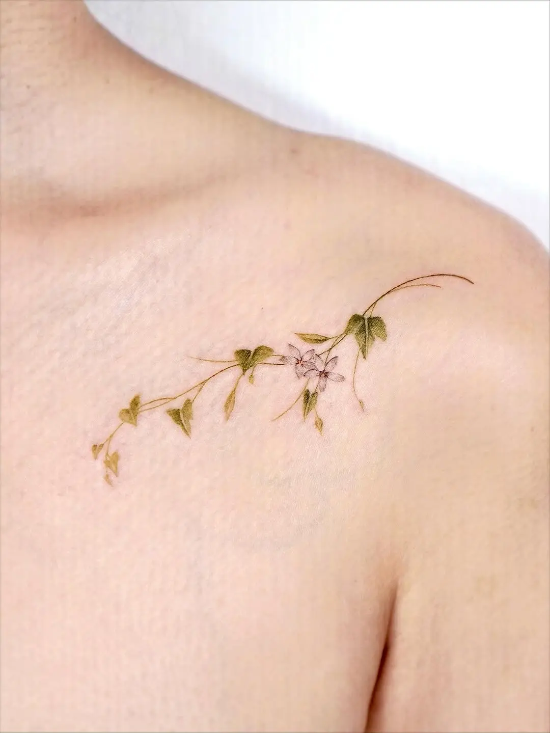 Delicate floral branch tattoo on shoulder area