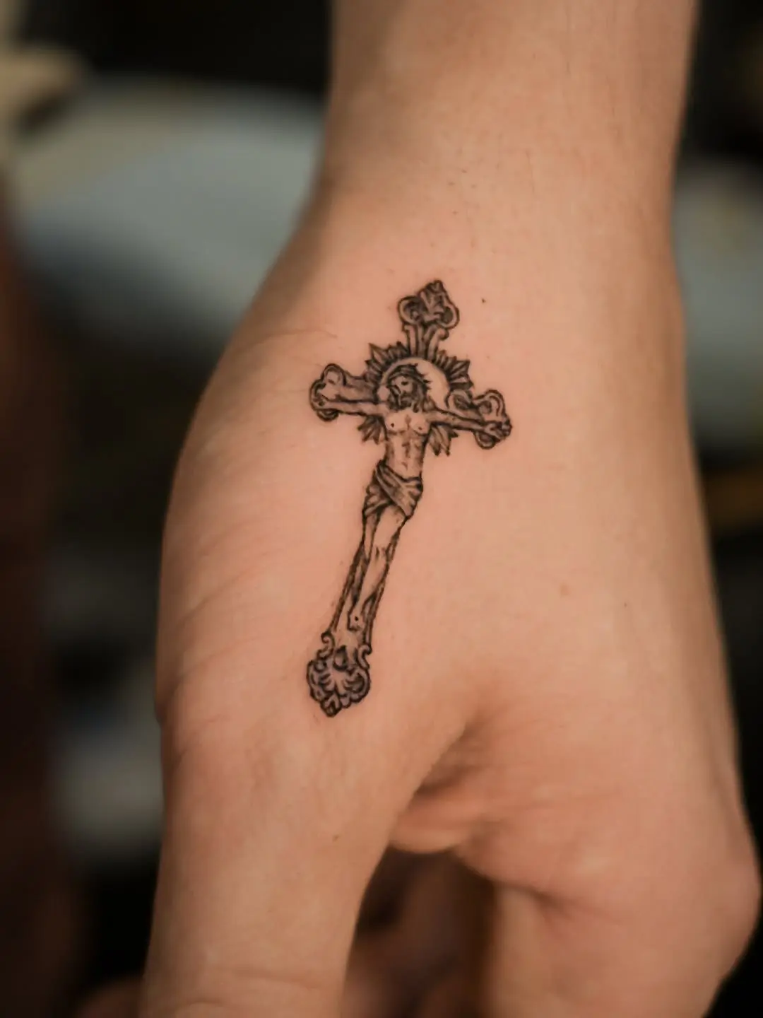 Intricate Christian cross tattoo on palm.