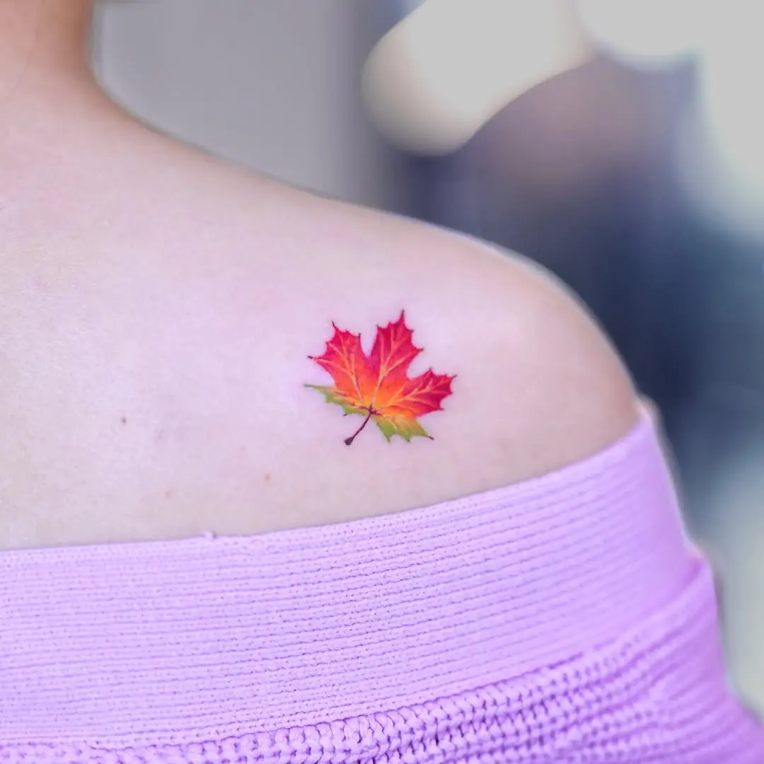 Vibrant maple leaf tattoo on shoulder area
