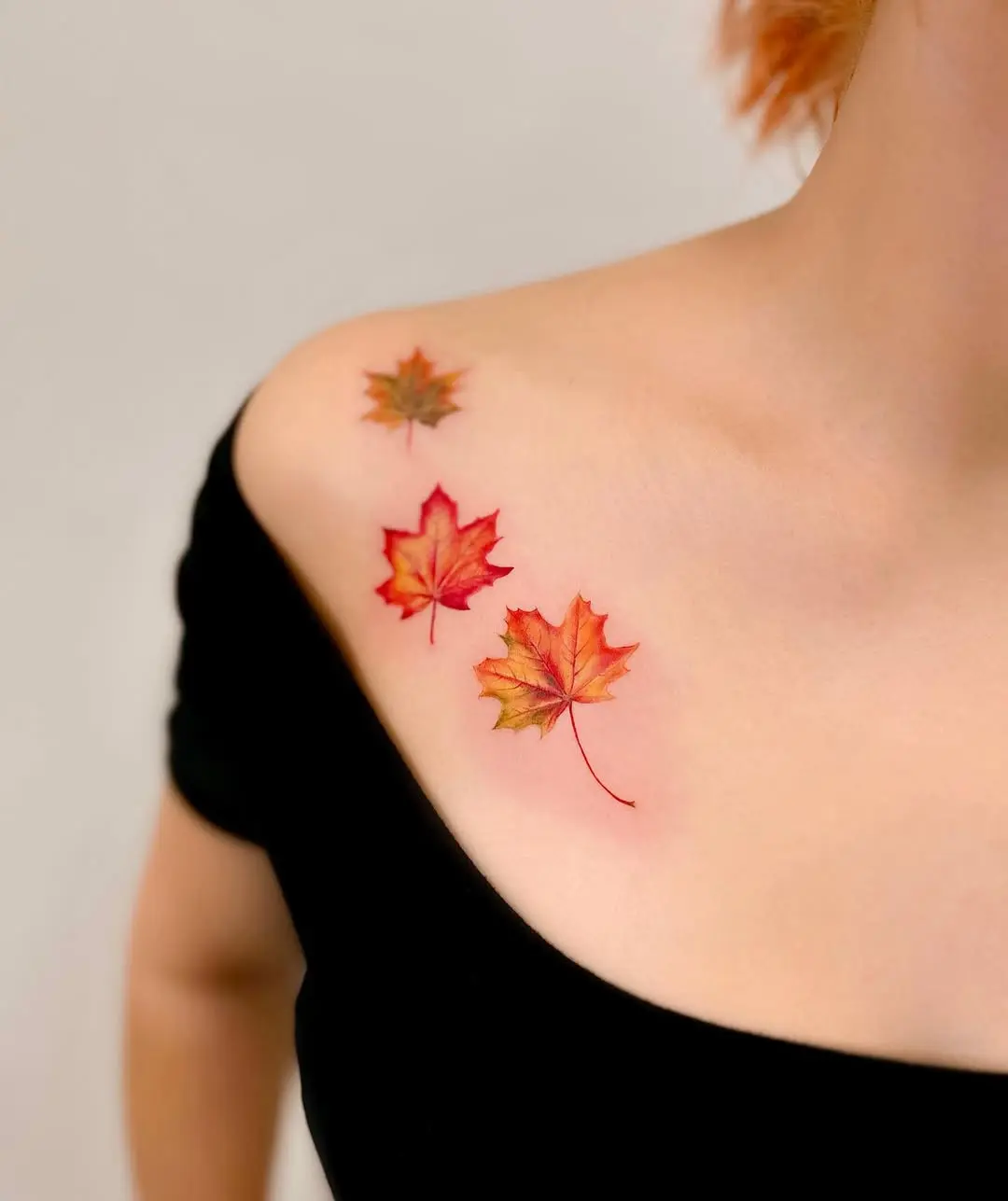 Vibrant autumn leaves tattooed on shoulder