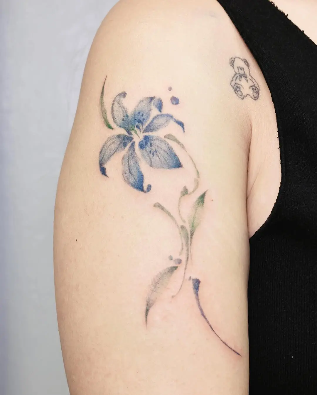 Graceful blue lily tattoo on the arm