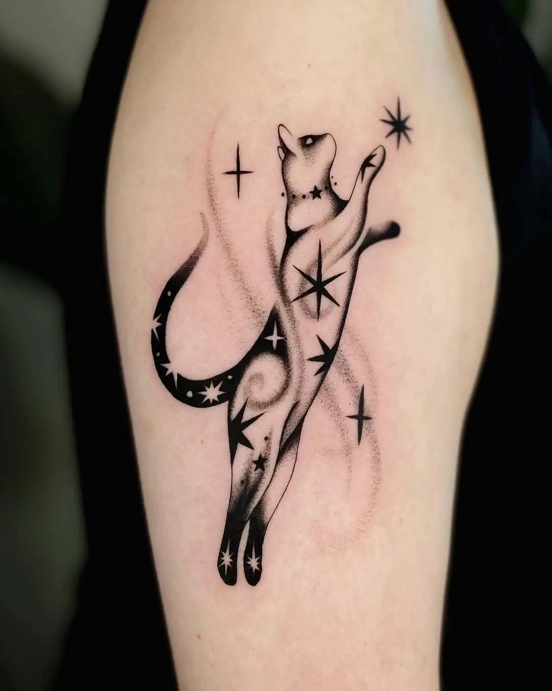 Playful cat tattoo amidst starry swirls