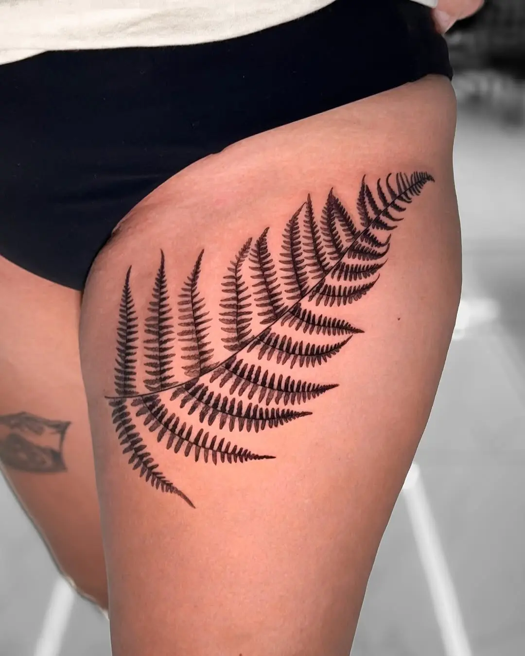 Elegant fern tattoo design on thigh