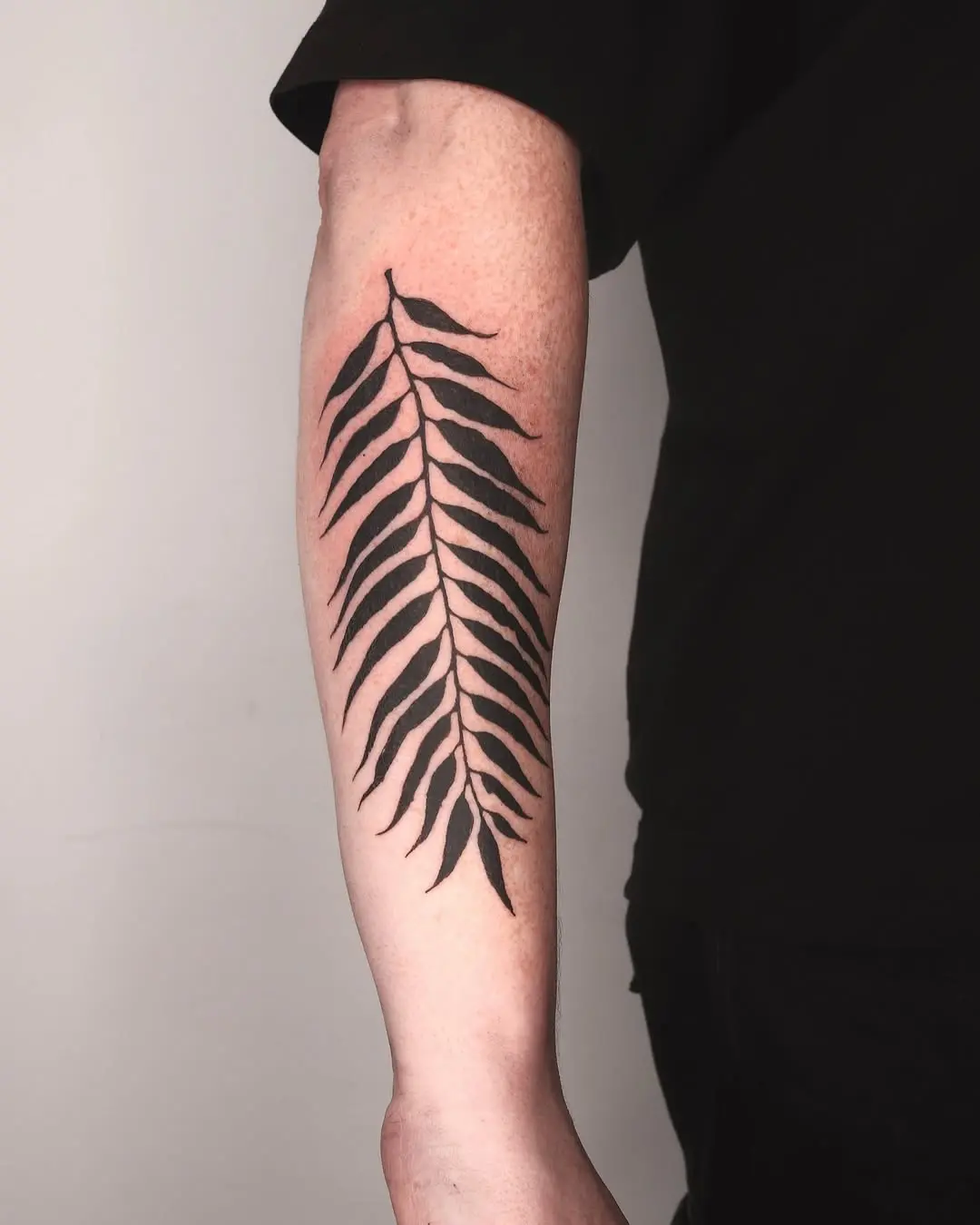 Elegant fern leaf tattoo in bold black ink