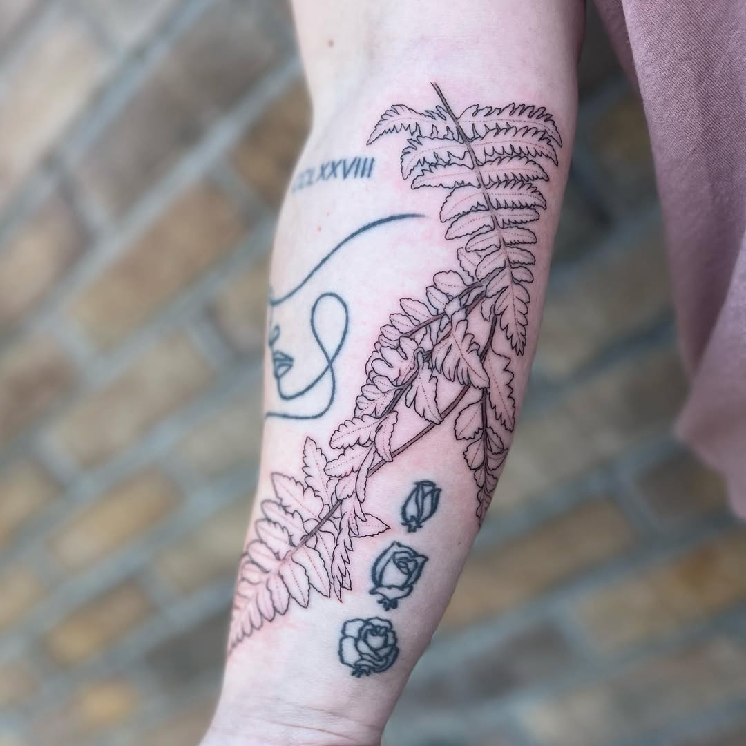 Delicate fern leaf tattoo with floral accents