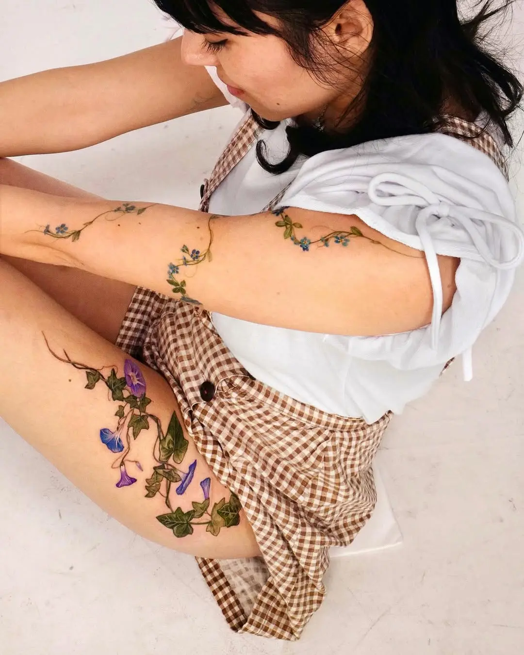 Colorful ivy tattoos on a woman's arms