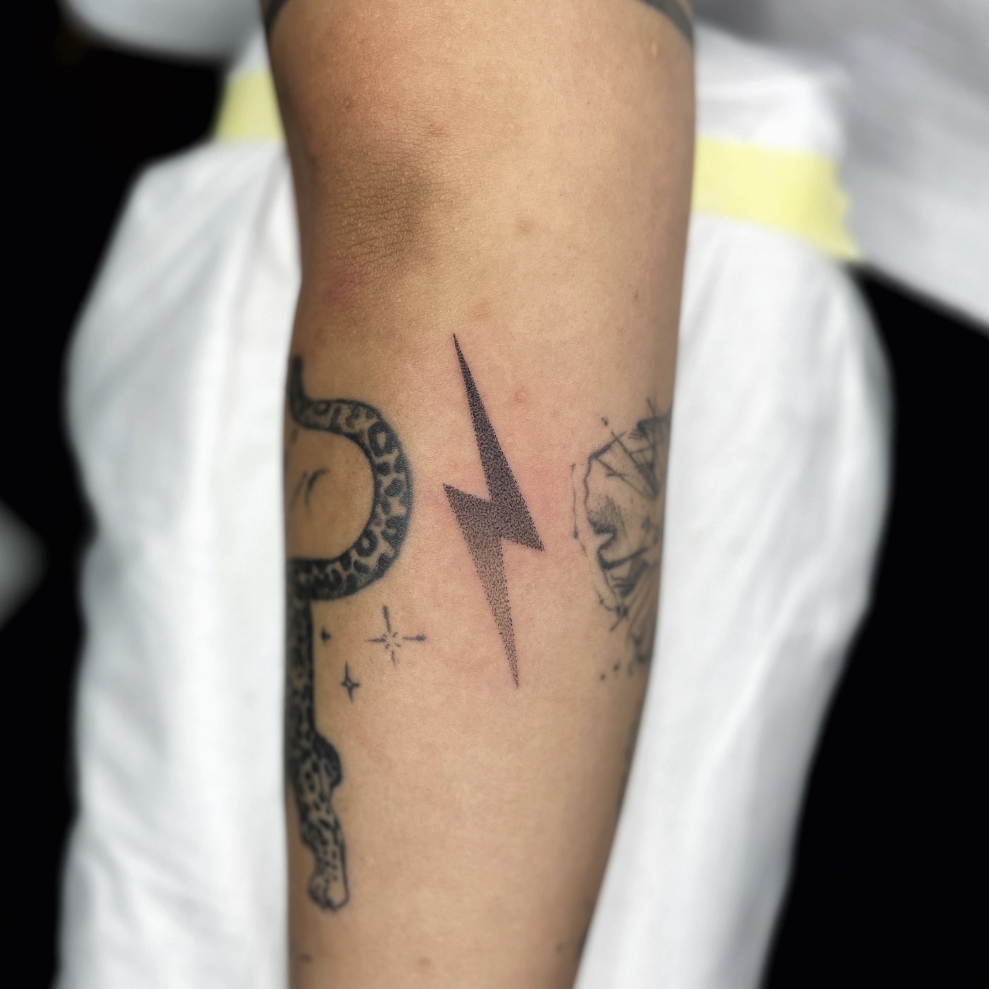 Minimalist lightning bolt tattoo on forearm
