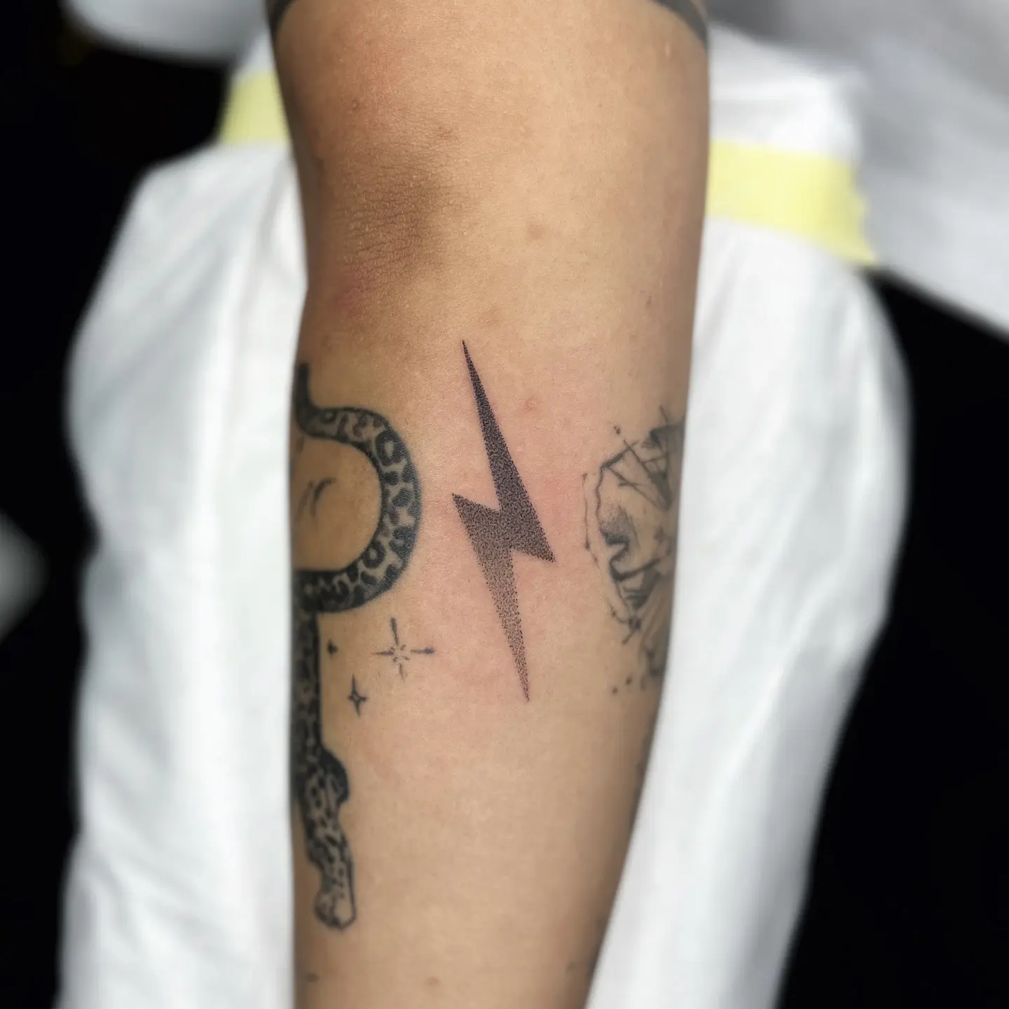 Minimalist lightning bolt tattoo on forearm