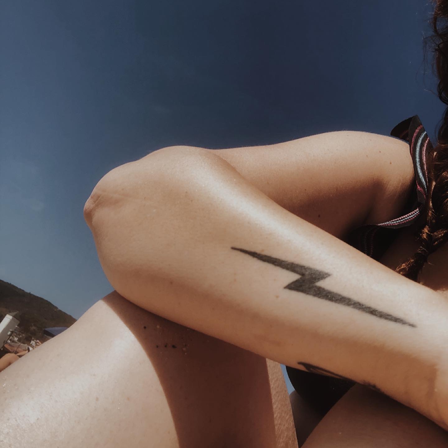 Sleek black lightning bolt tattoo on arm