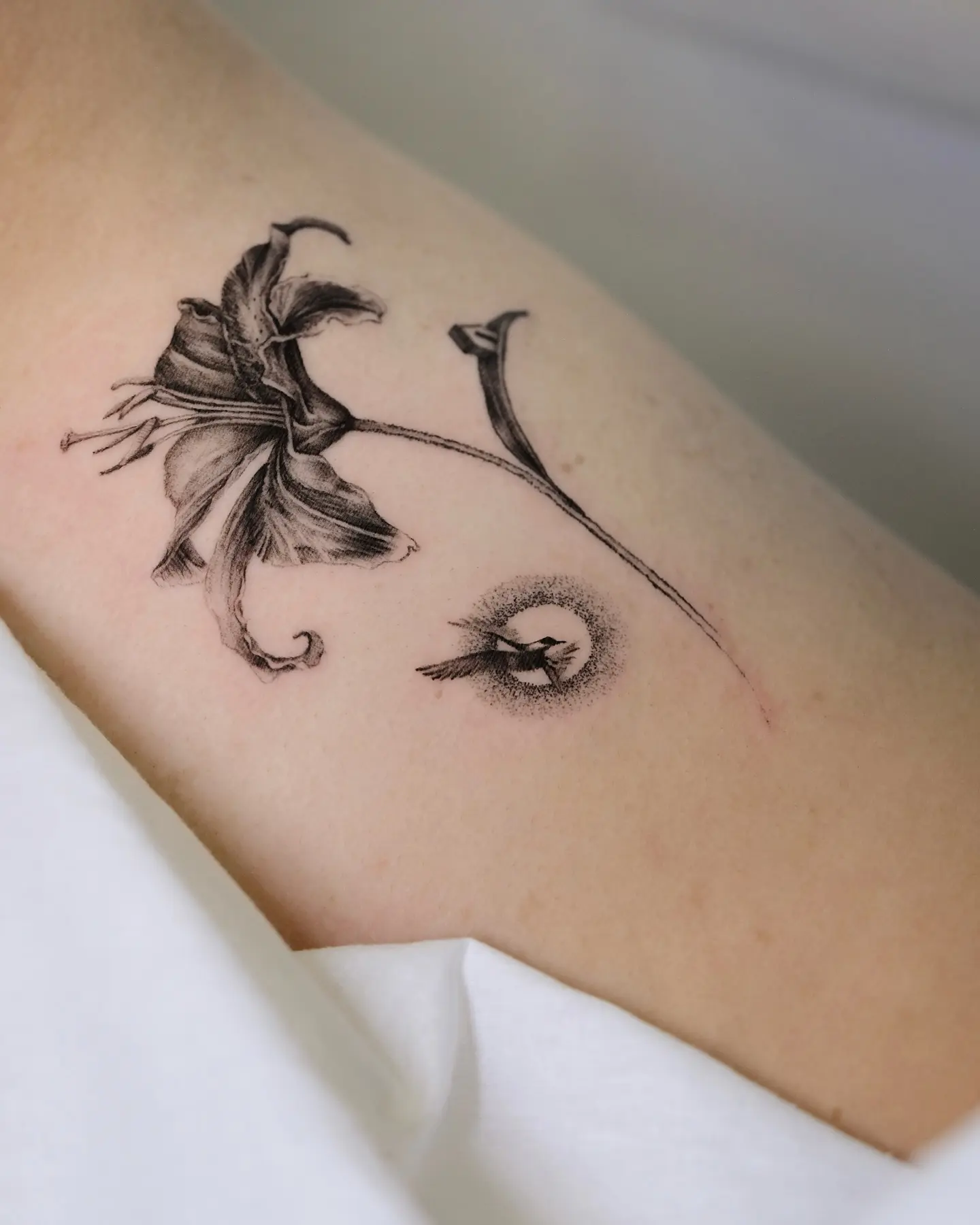 Elegant black ink lily tattoo with fine details