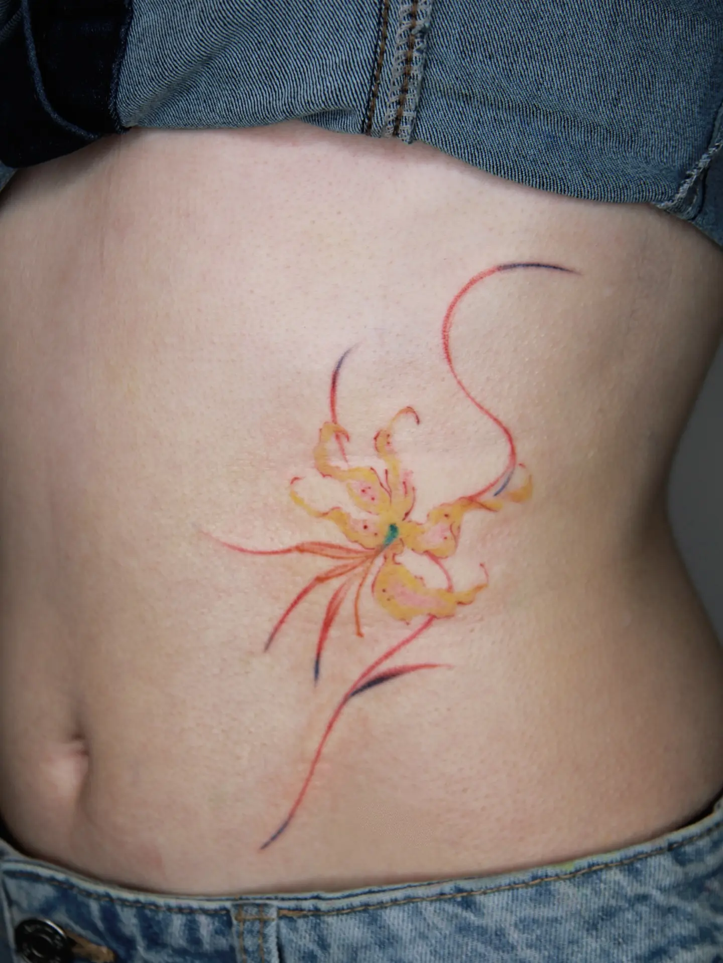 Vibrant lily tattoo on the lower back