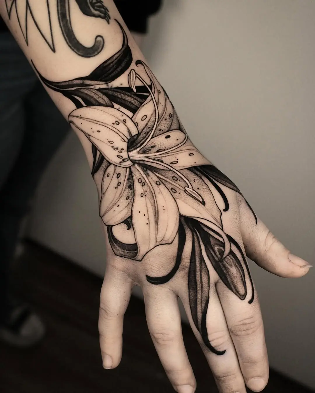 Stunning black ink lily tattoo on hand