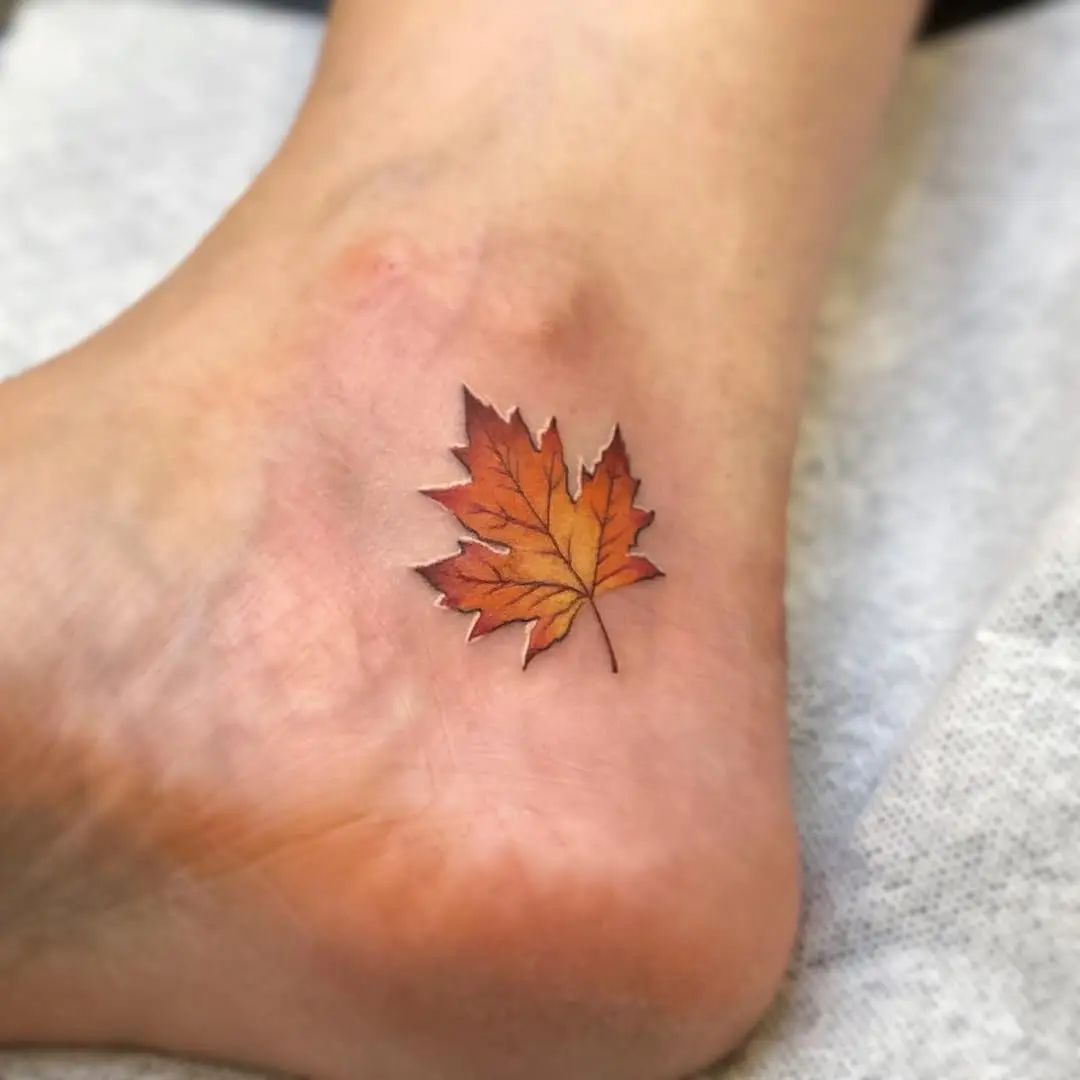 Vivid maple leaf tattoo on ankle area