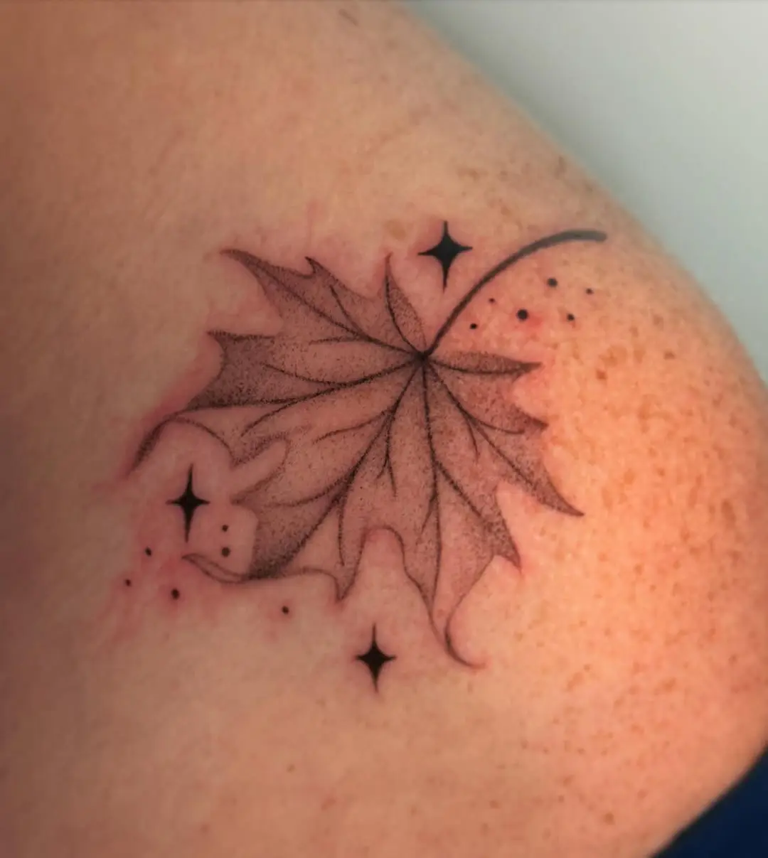 Artful maple leaf tattoo with stars design