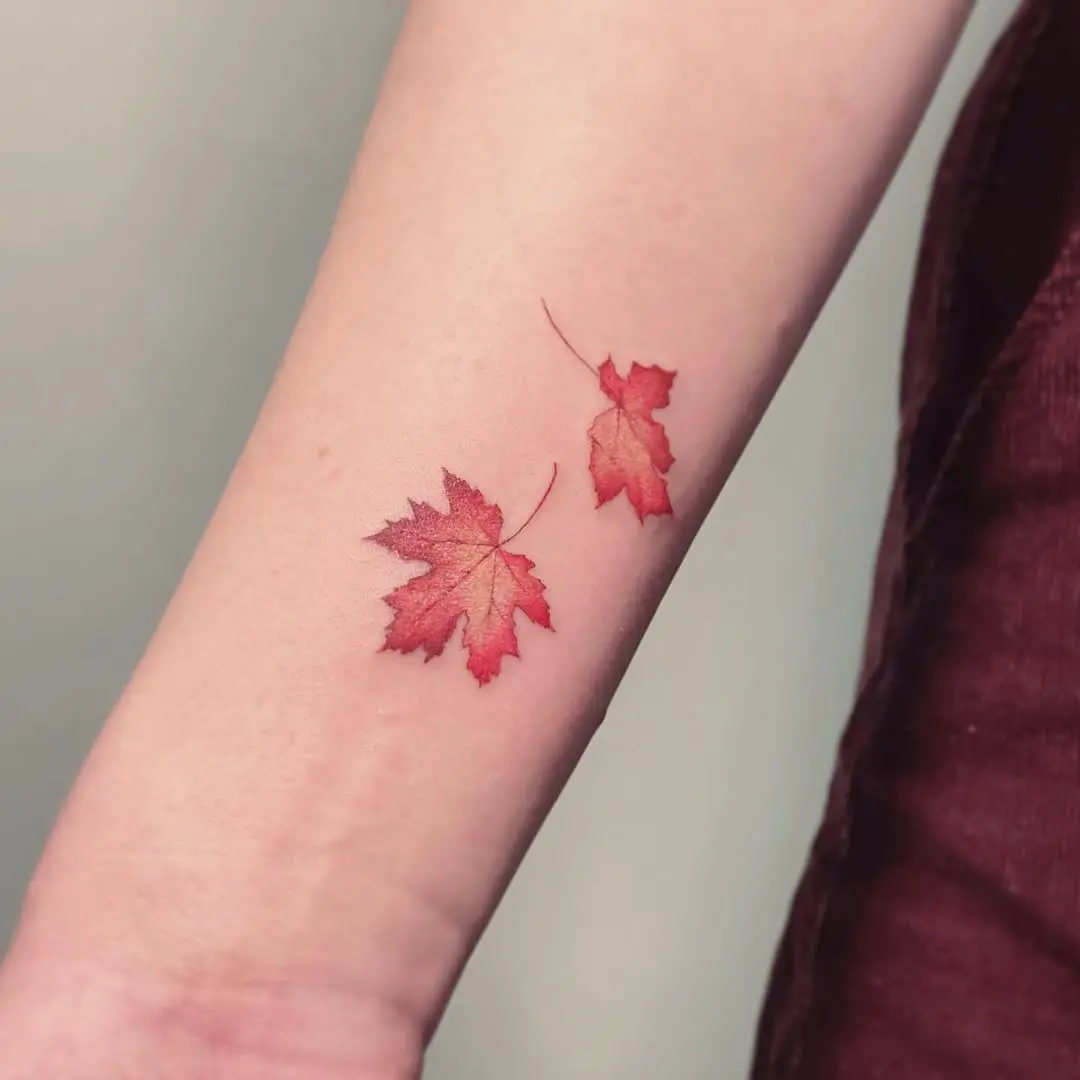 Delicate red maple leaf tattoo on arm
