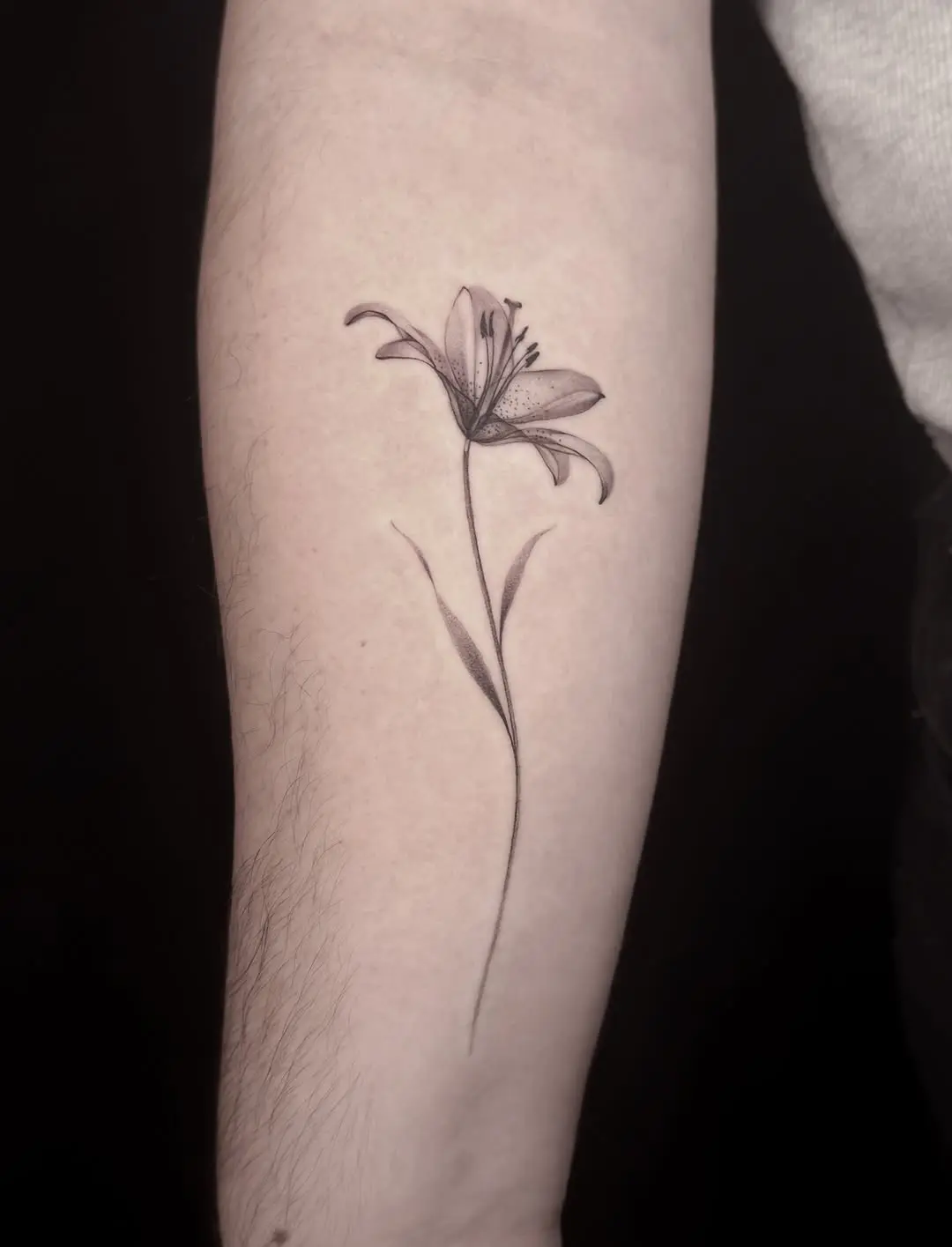 Elegant minimalist lily tattoo design on arm