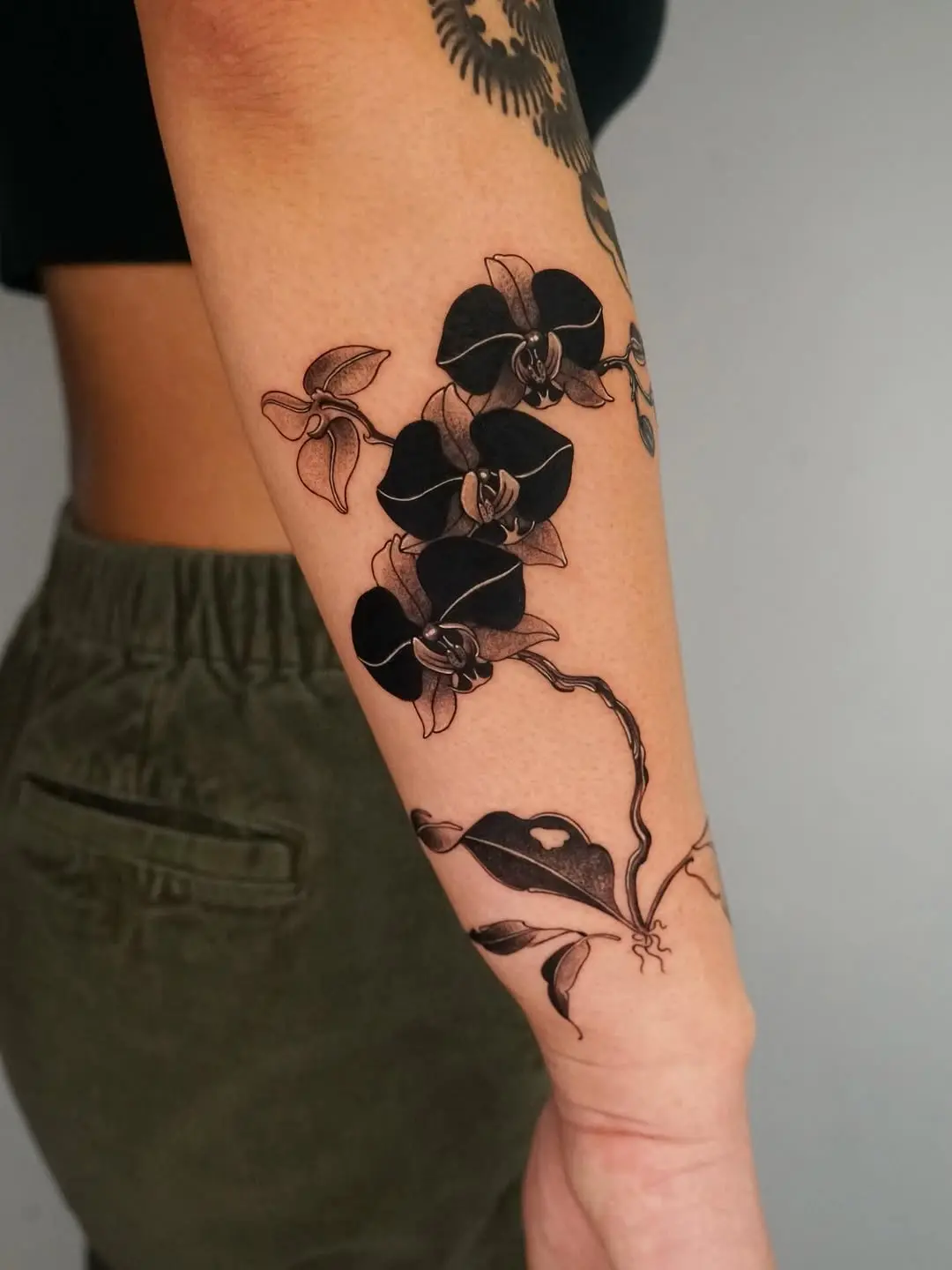 Elegant black orchid tattoo on forearm