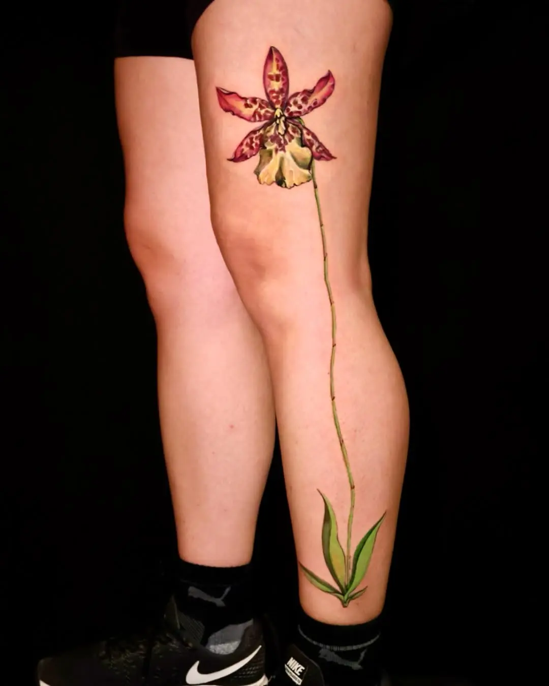 Stunning orchid tattoo gracing the leg