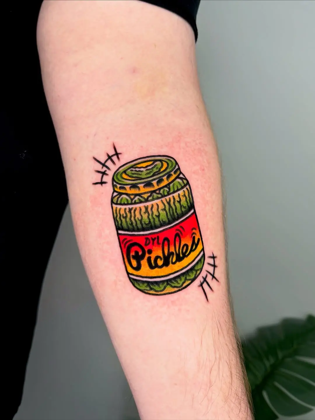 Vibrant pickle jar tattoo with bold colors