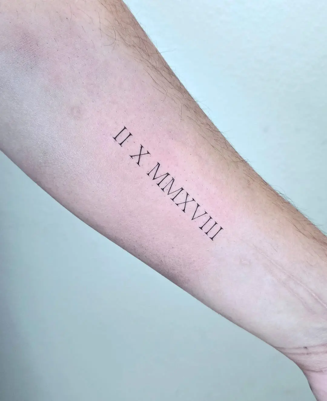 Minimalist Roman Numeral Tattoo on Forearm