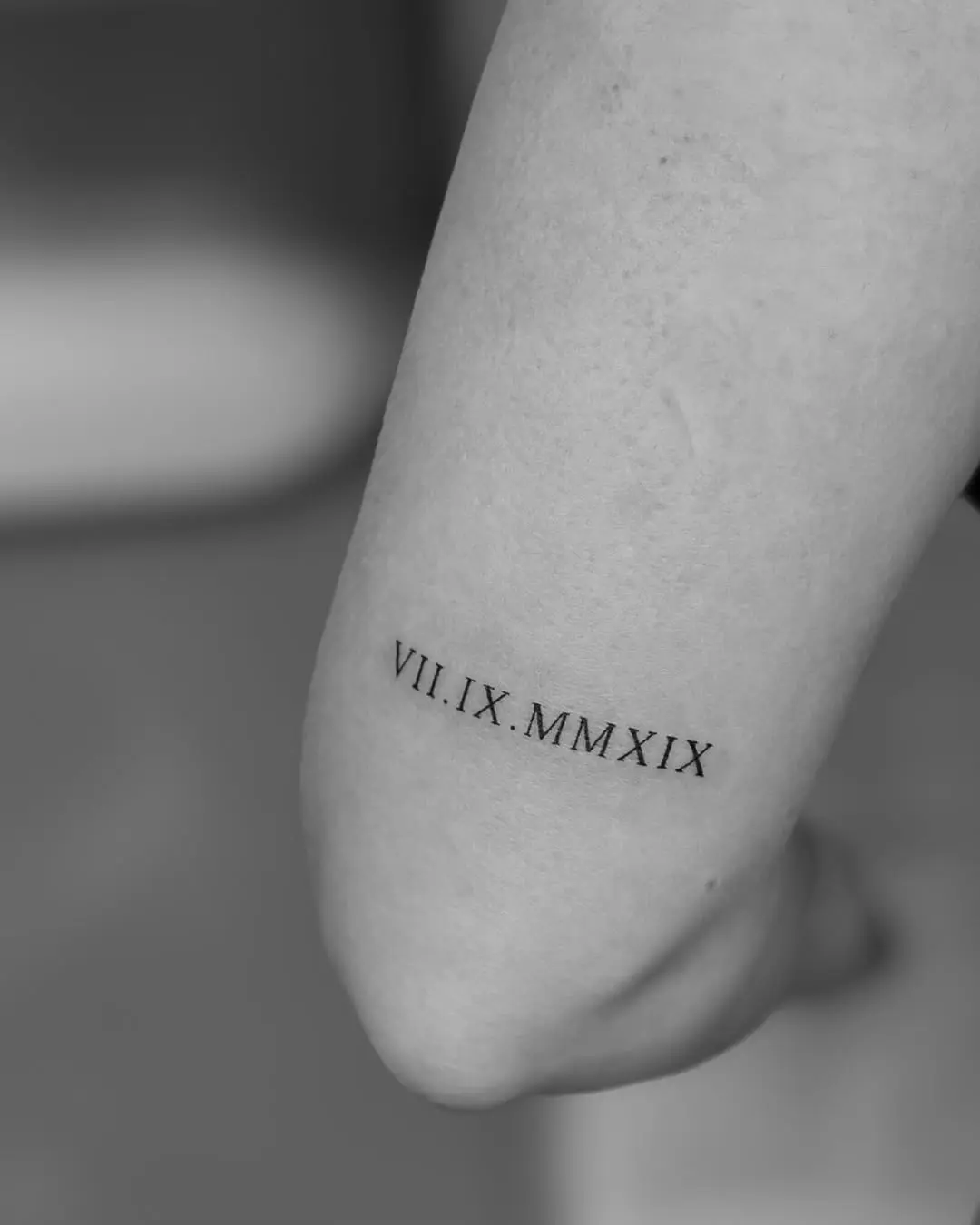 Minimalist roman numeral tattoo on the forearm
