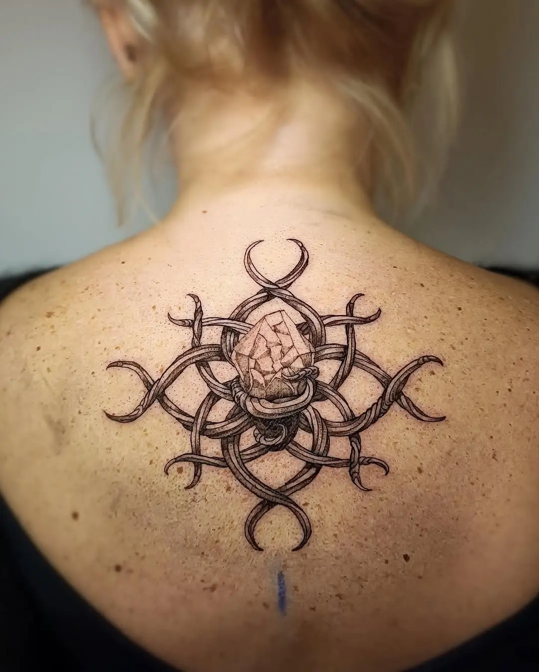 Intricate roots tattoo with crystal centerpiece