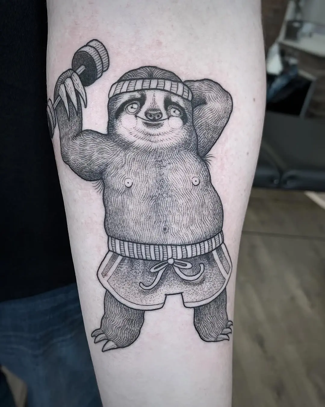 Playful sloth flexing with a dumbbell tattoo
