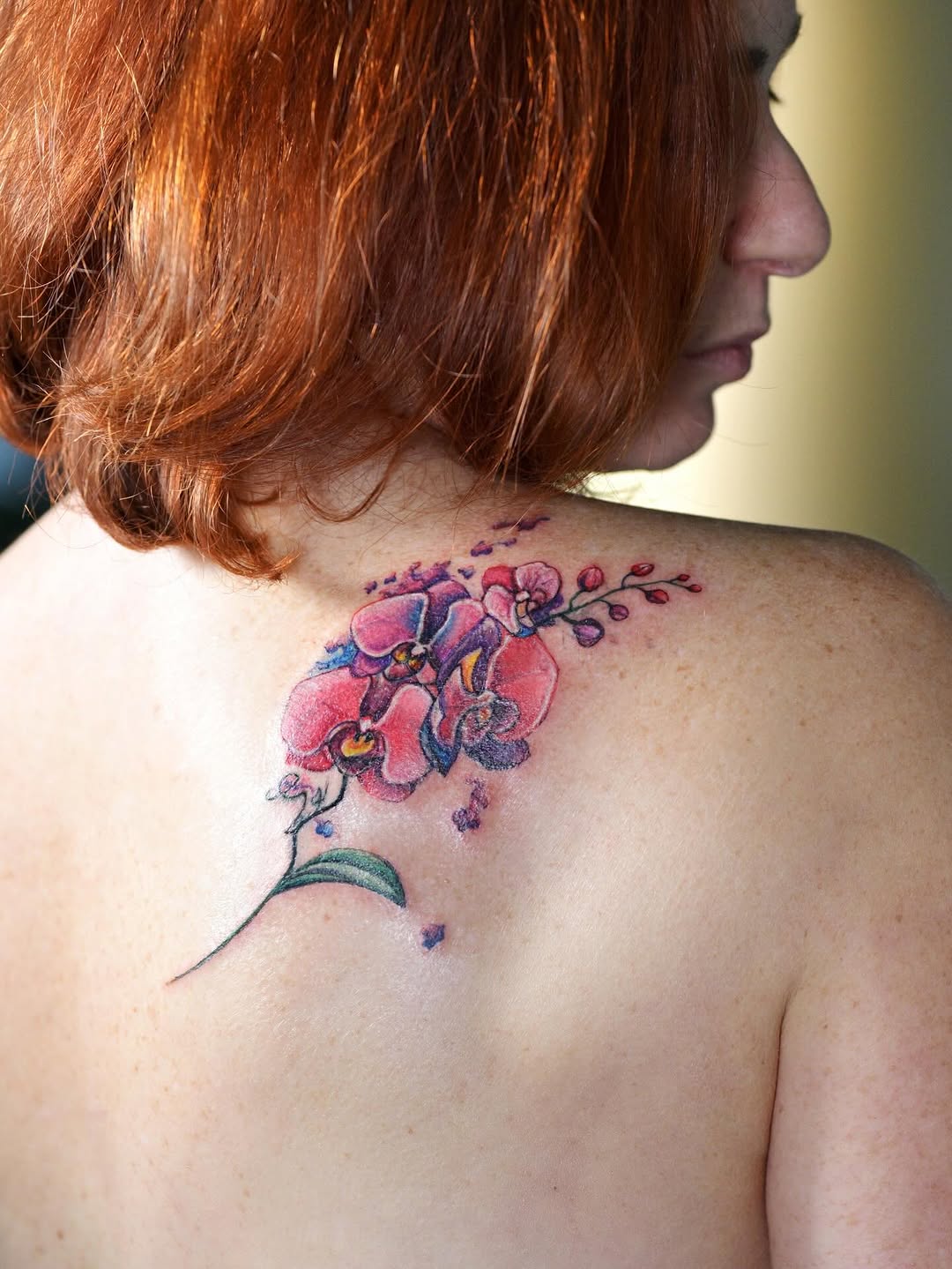 Elegant orchid tattoo design on shoulder blade