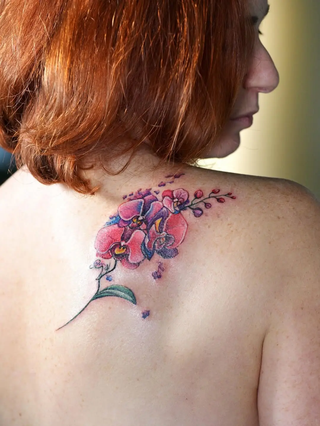 Elegant orchid tattoo design on shoulder blade