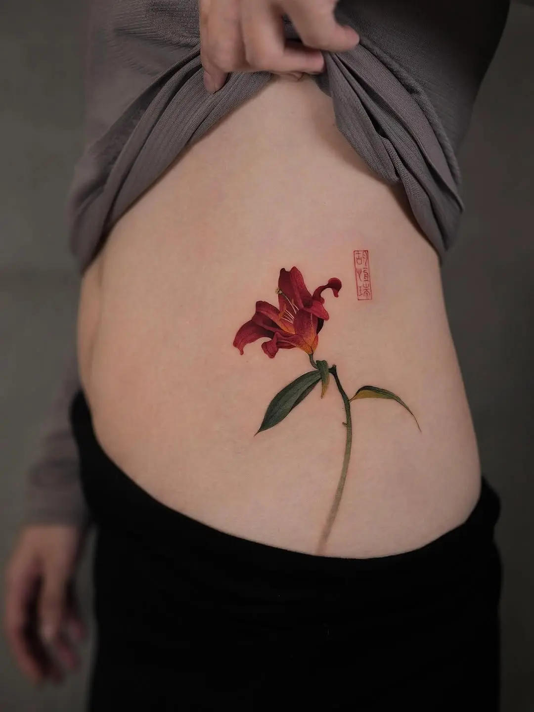 Stunning side tattoo of a vibrant lily blossom.