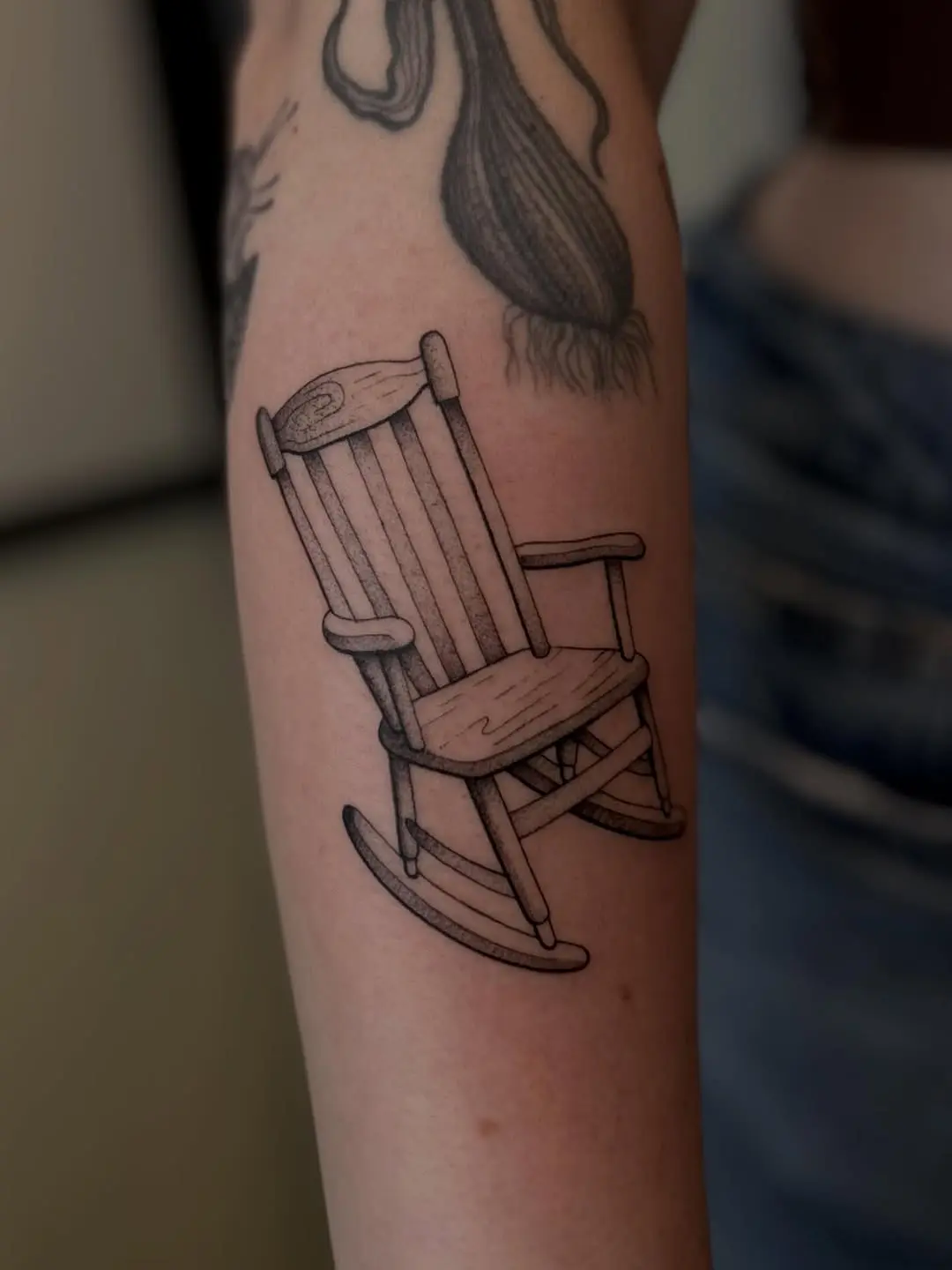 Charming rocking chair tattoo in black ink