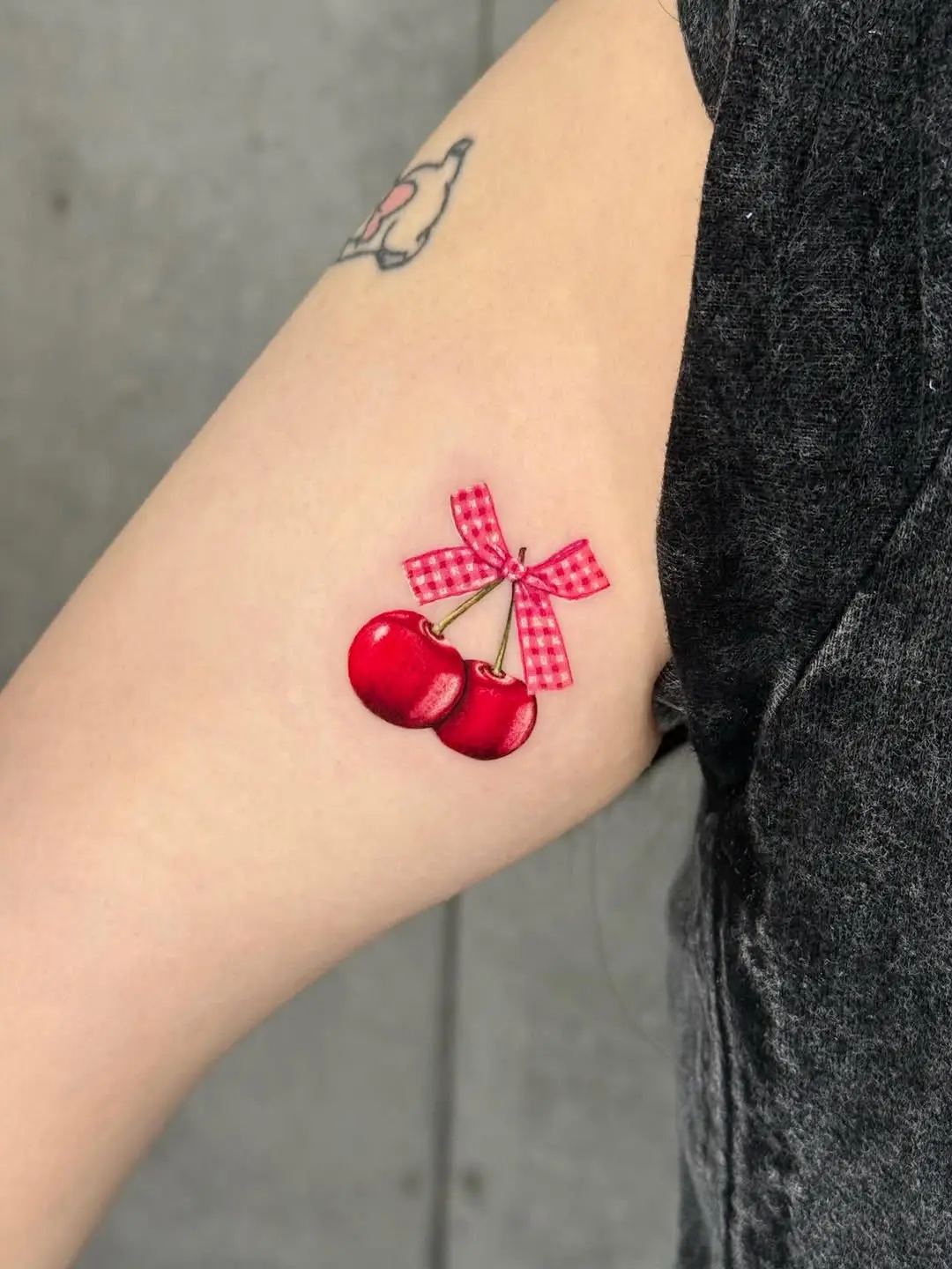 Charming Cherry Tattoo with a Playful Bow
