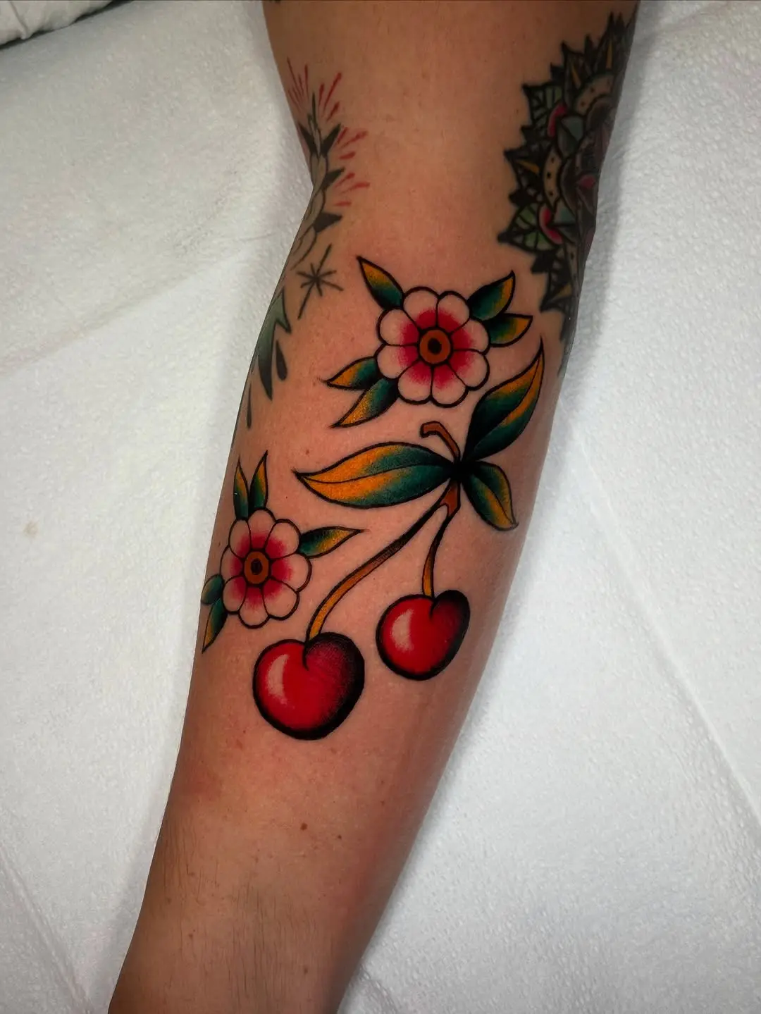 Vibrant cherry tattoo with floral accents