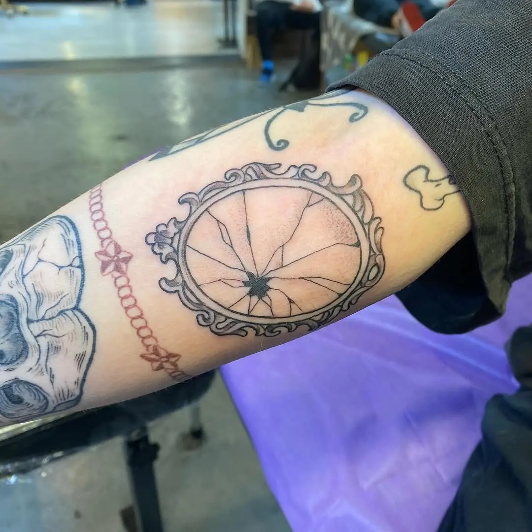 Intricate cracked mirror tattoo design on forearm