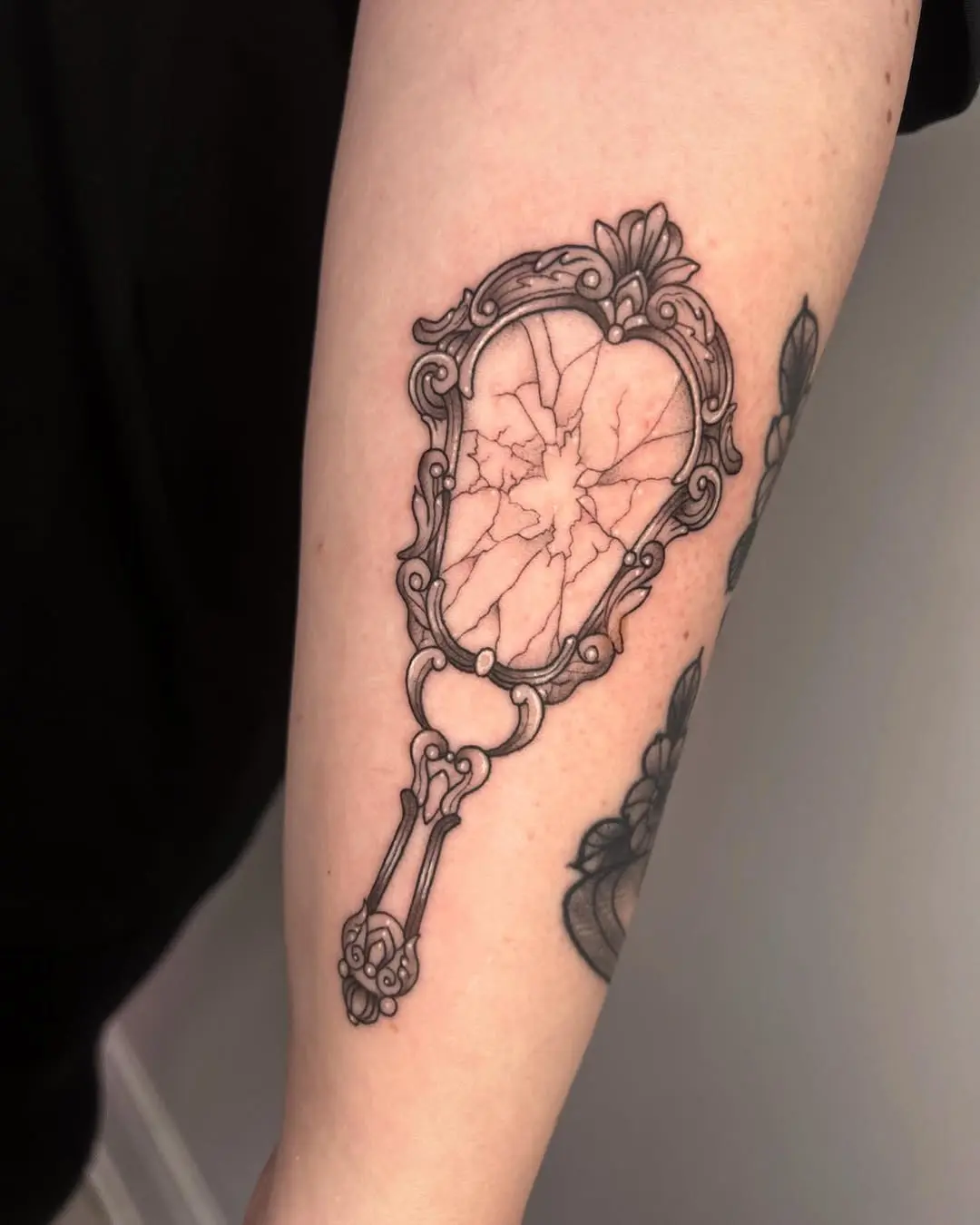 Intricate cracked mirror tattoo design on arm
